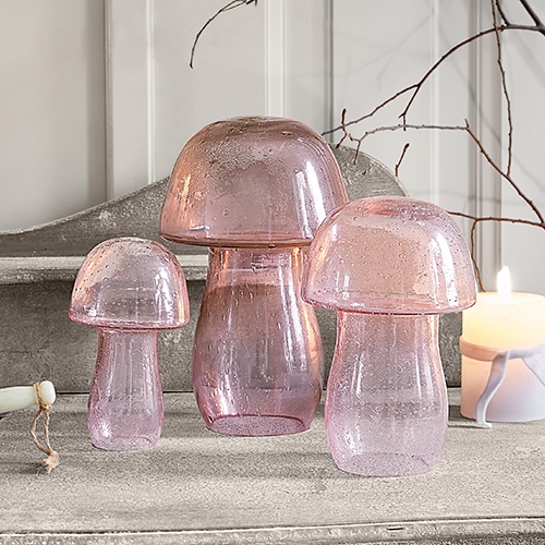 Drei dekorative Pilze aus rosa Glas auf grauer Oberfläche, stilvolle Wohnraumdeko
