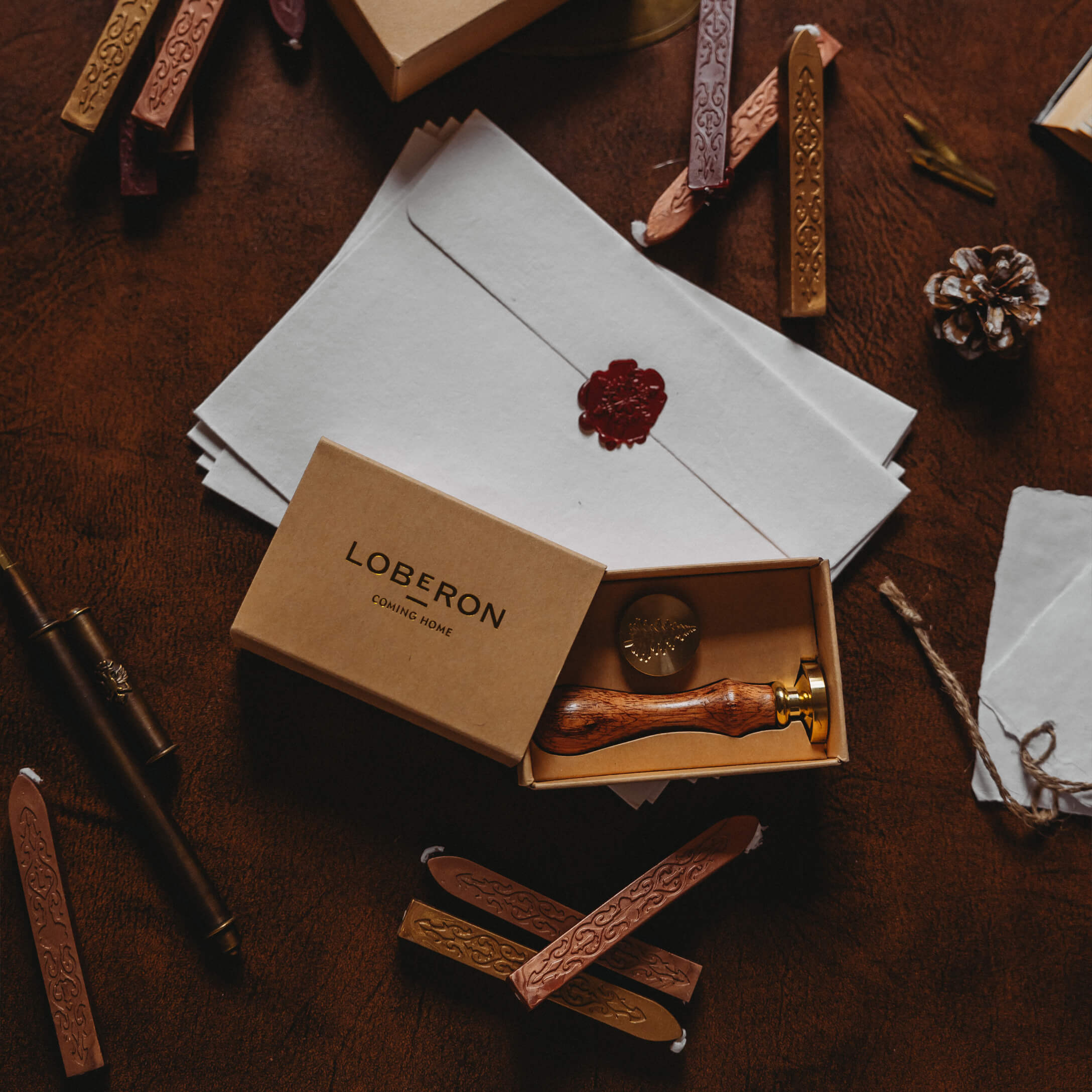 Siegelset mit Holzgriff und Wachsstangen auf braunem Untergrund mit Briefumschlägen