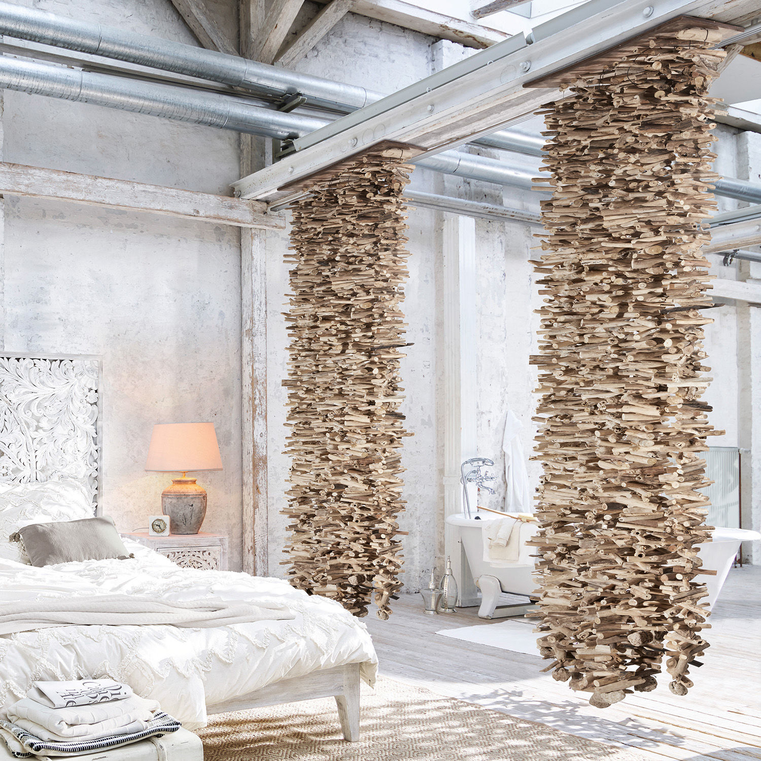Loft-Schlafzimmer mit weißem Bett und dekorativen Holzsäulen vor hellen Wänden