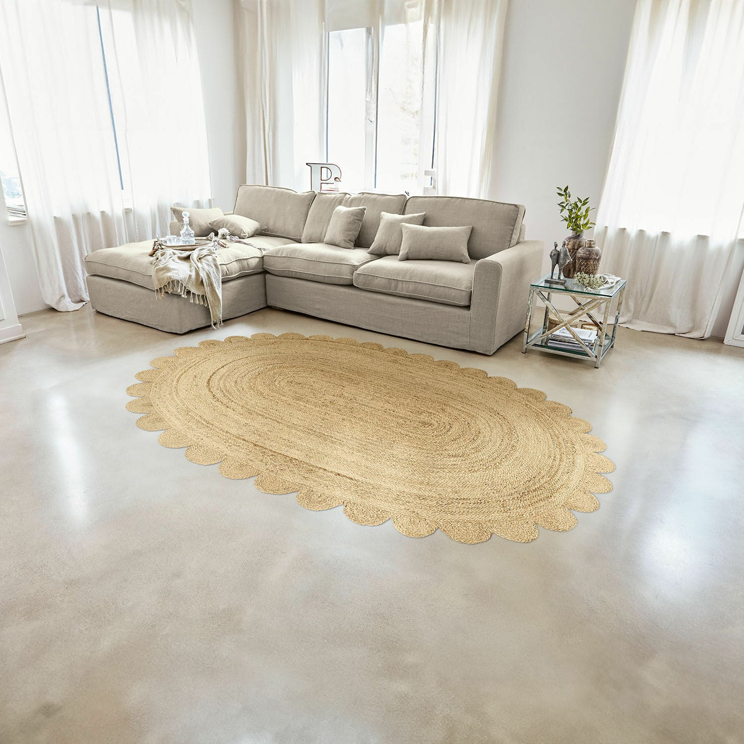 Teppich Ferce Ovaler Teppich aus Jute in Naturfarbe mit gewelltem Rand im hellen Wohnzimmer mit beigem Sofa