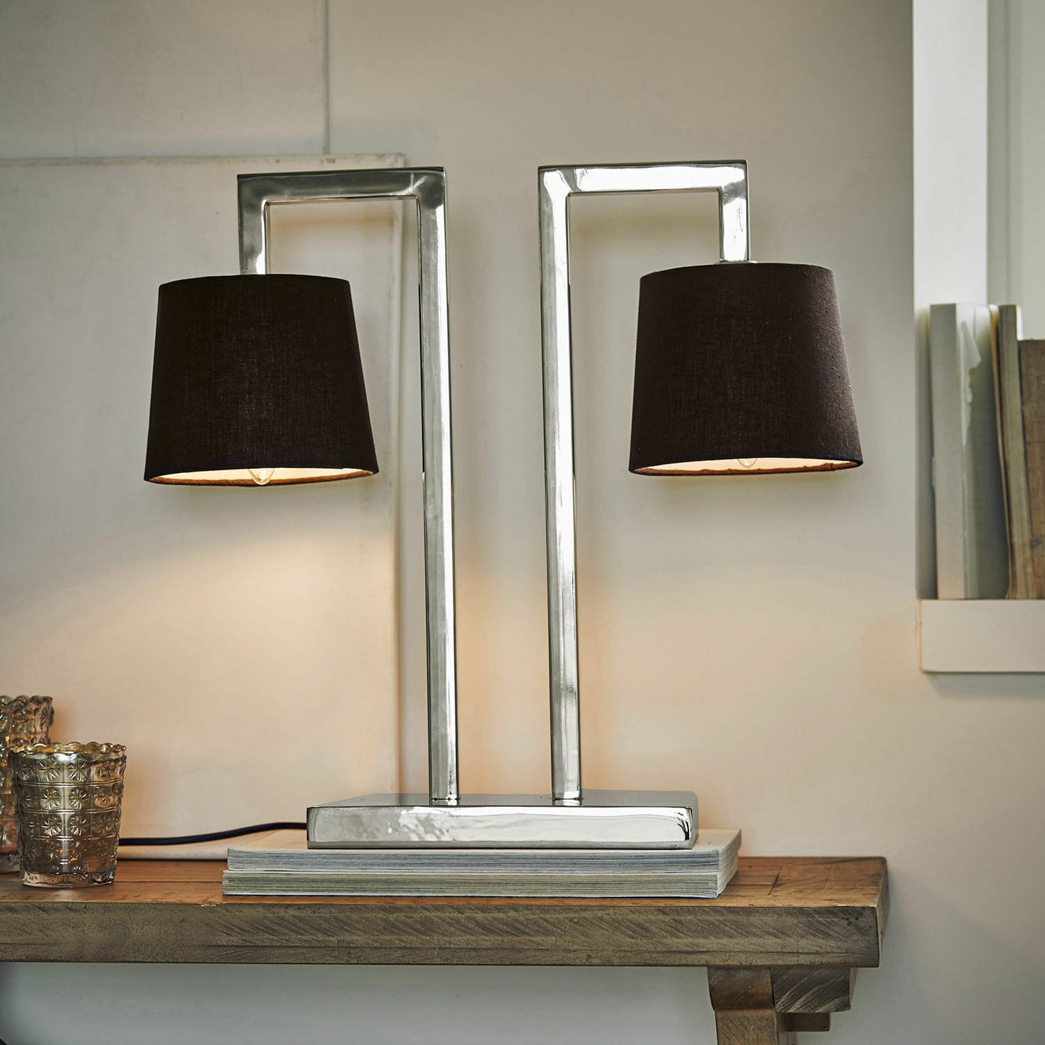 Moderne Tischlampe mit Metallbasis und zwei schwarzen Lampenschirmen auf Holztisch