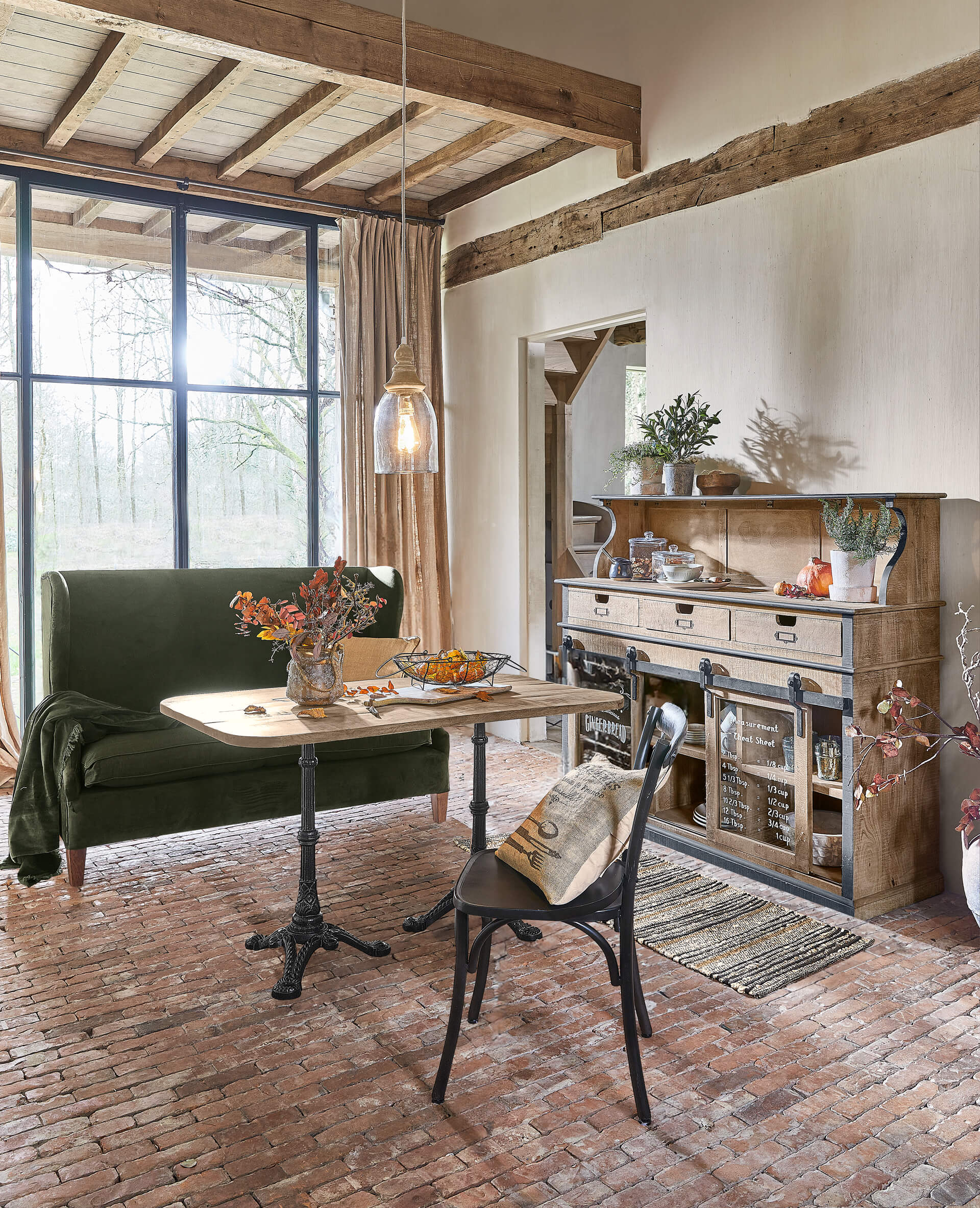 Esszimmer mit Holztisch, grünem Samtsofa und rustikalem Sideboard aus Holz und Metall