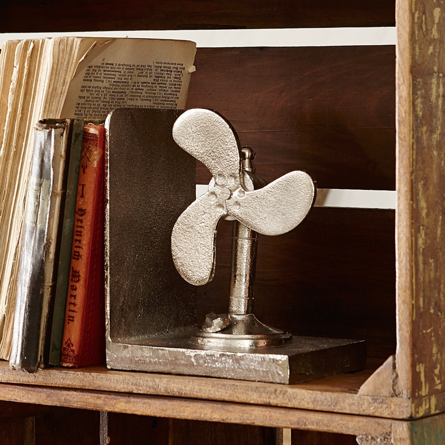 Silberne Metall-Buchstütze mit Ventilator-Design auf vintage Holzregal
