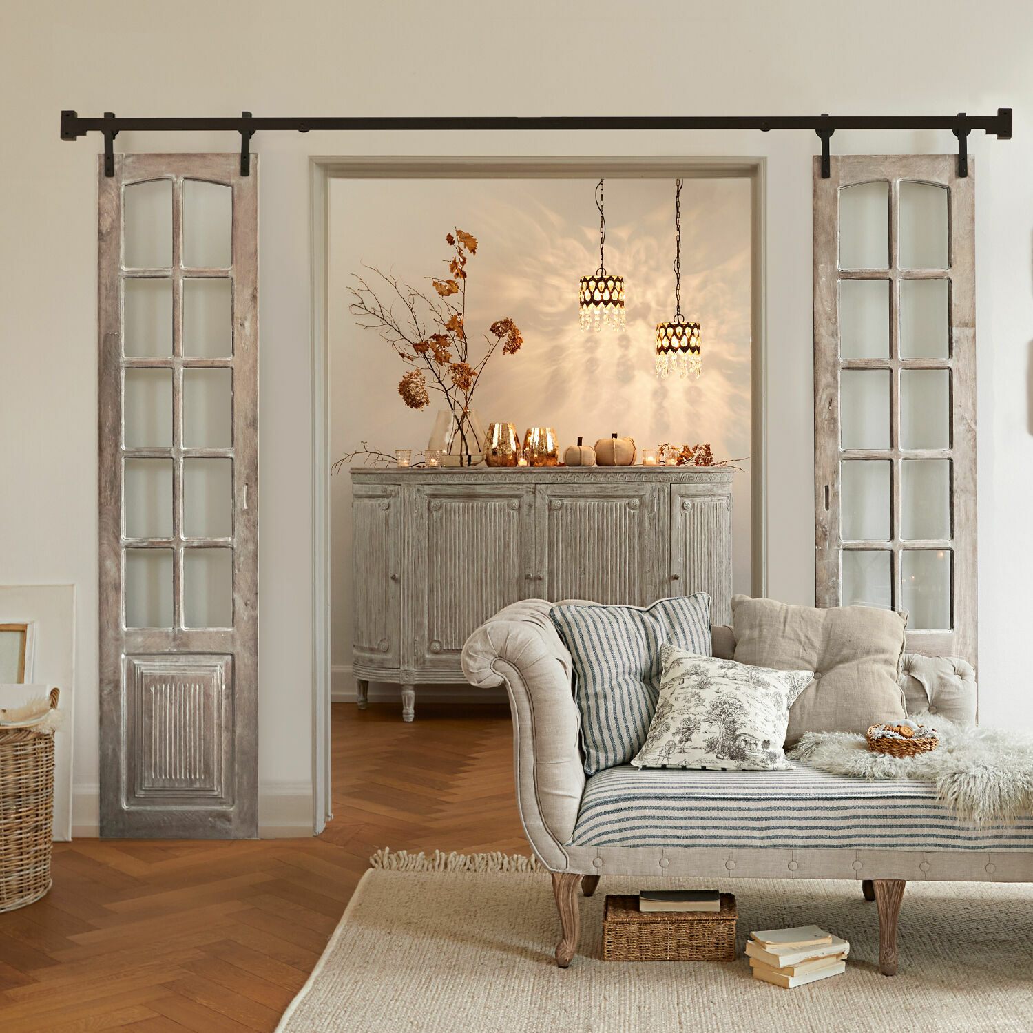 Gemütliches Wohnzimmer mit gestreiftem beigem Sofa und vintage Holzkommode auf Fischgrätparkett.