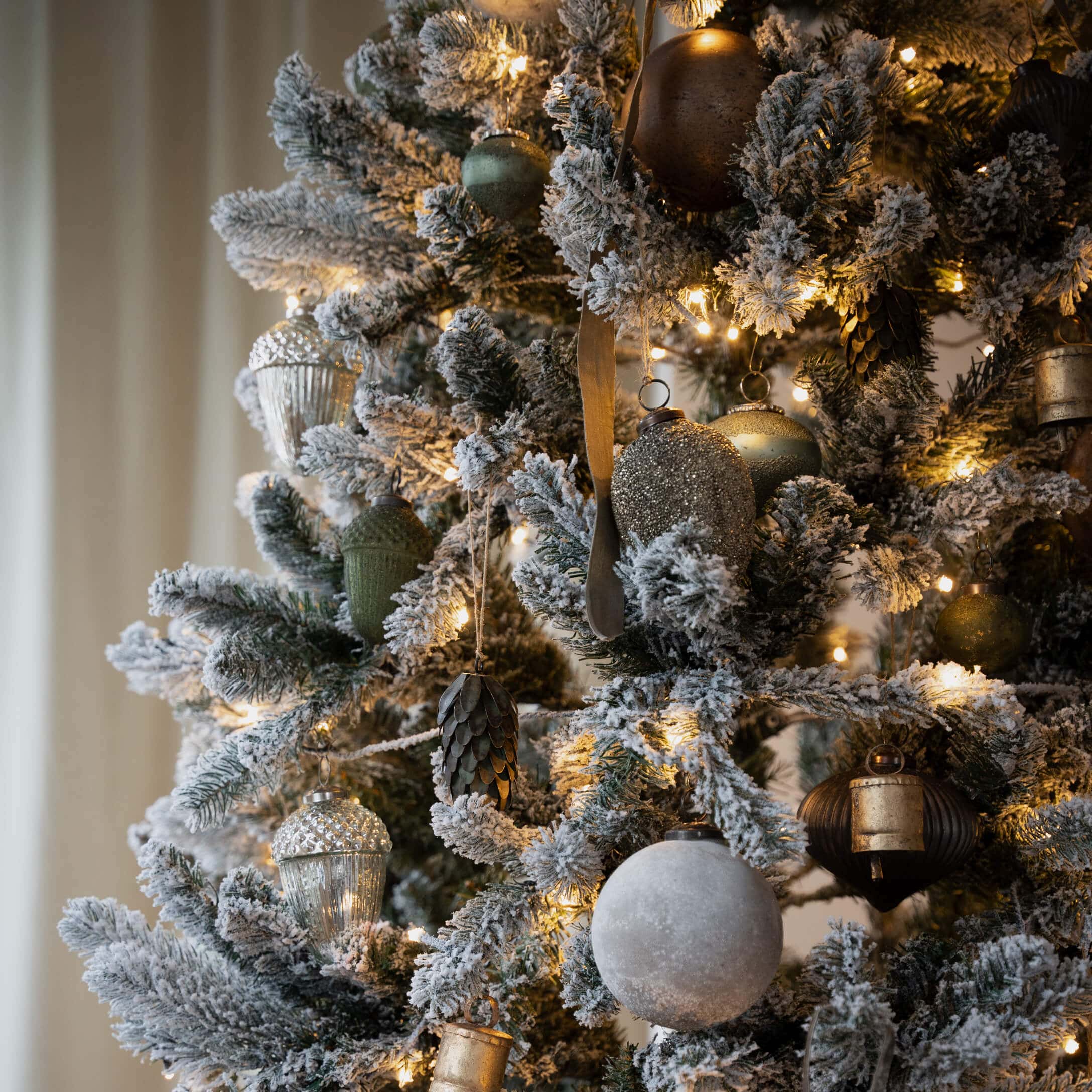 Künstlicher Weihnachtsbaum mit weißem Schnee und gold-grünen Kugeln, festliche LED-Dekoration