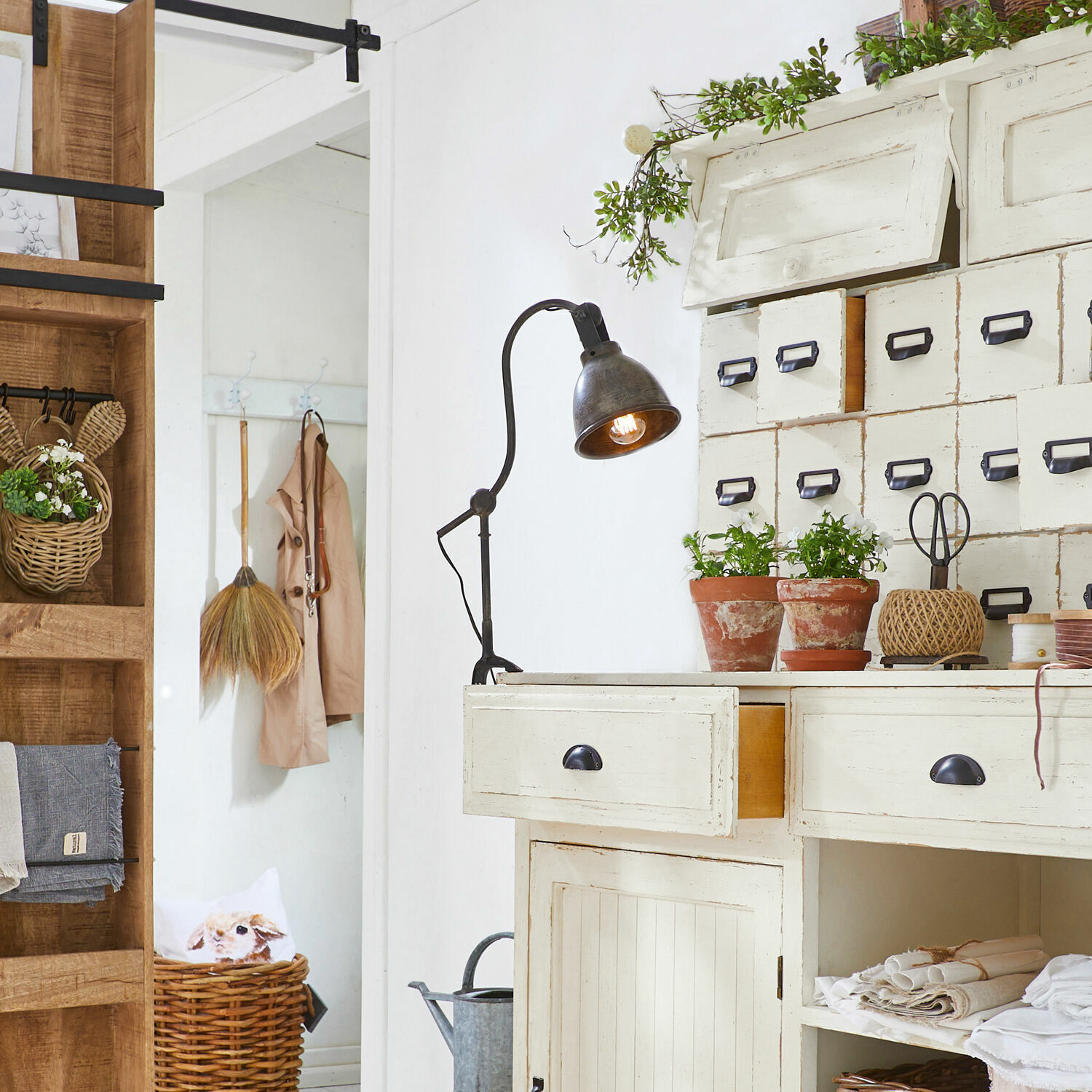 Weißes Holzschreibtisch mit Schubladen und vintage Metalllampe, Pflanzen und Körbe als Dekor