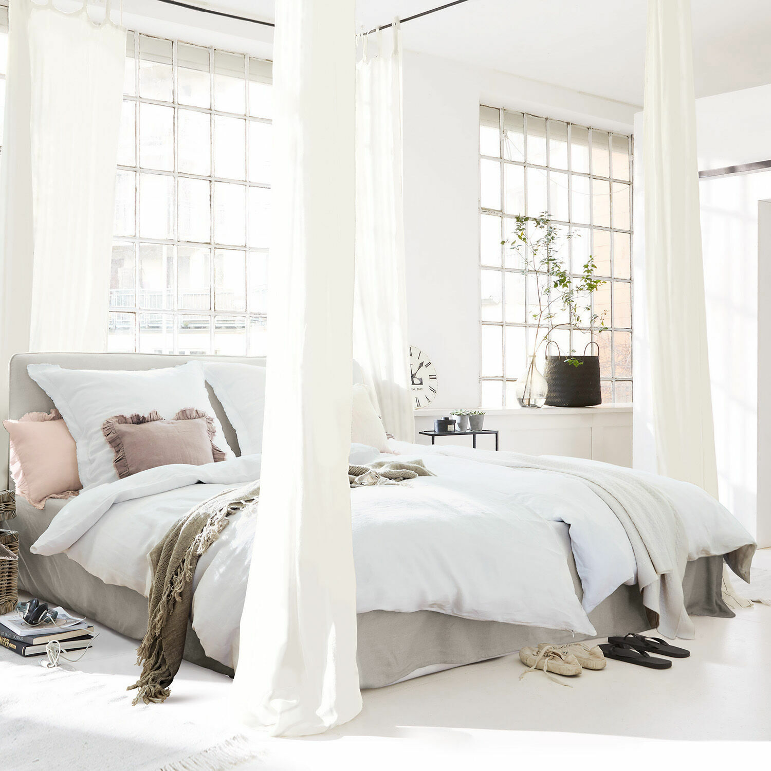 Gemütliches Bett mit weißer Bettwäsche und beiger Decke in hellem, modernem Schlafzimmer