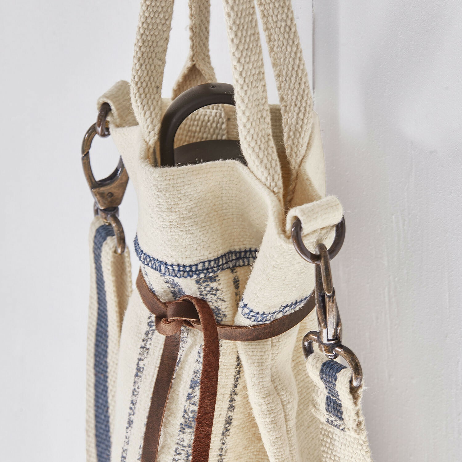 Beige Stofftasche mit blauen Streifen und braunem Lederband, robuste Metallbeschläge