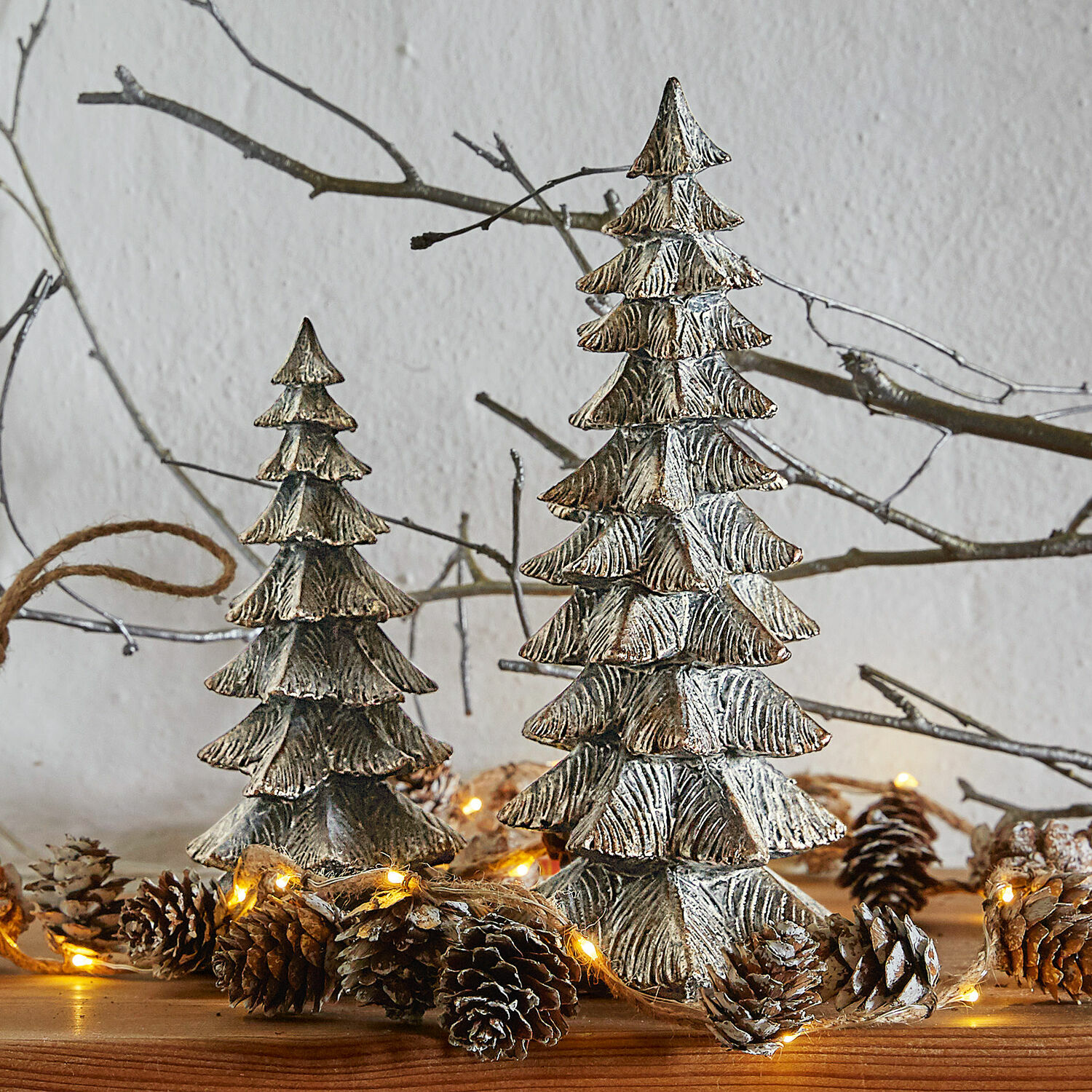 Deko-Baum 2er Set Calavi Dekorative silberne Metall-Weihnachtsbäume auf Holztisch mit Lichterkette und Tannenzapfen