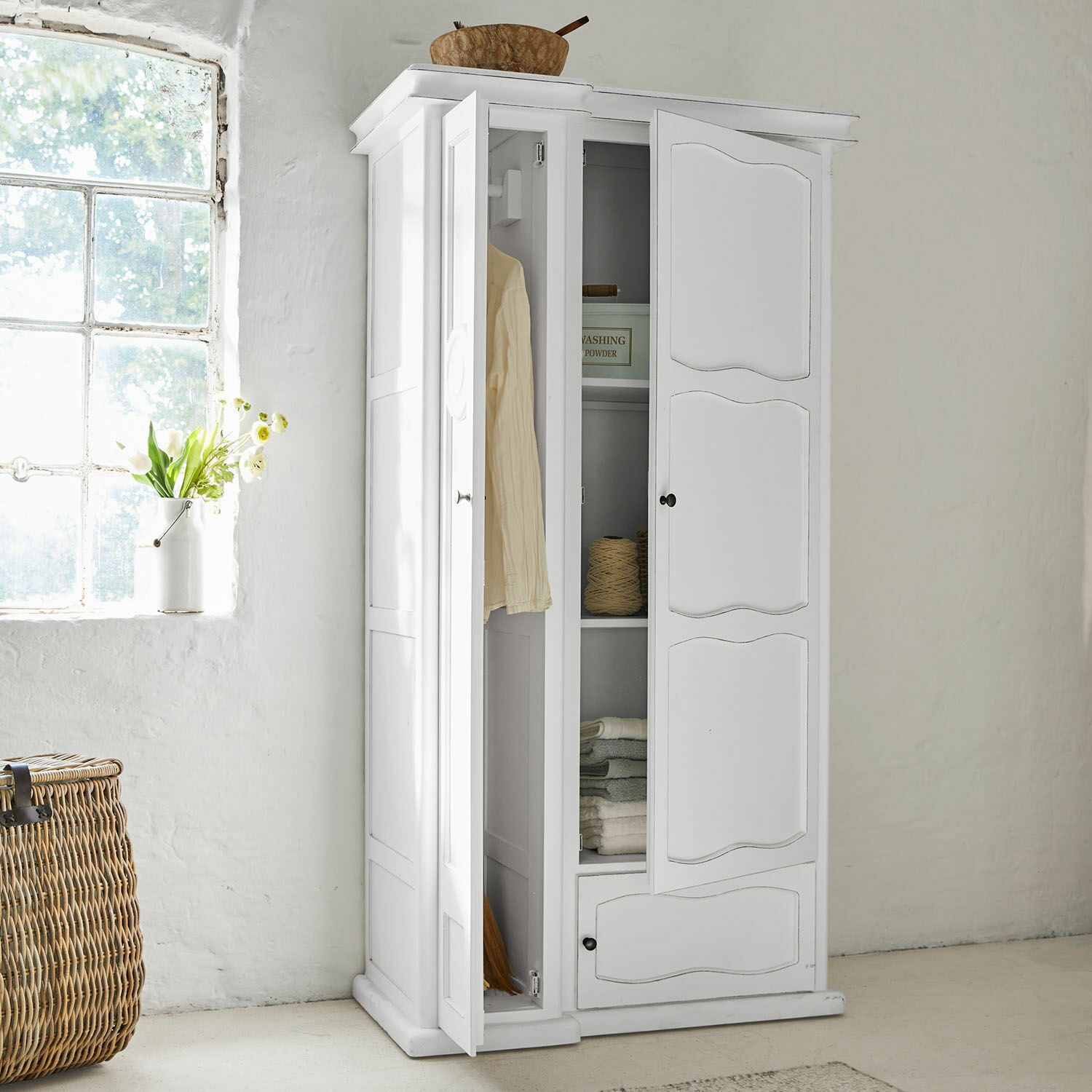 Weißer Holzschrank mit offenen Türen, Regalen und Kleiderstange in hellem Raum