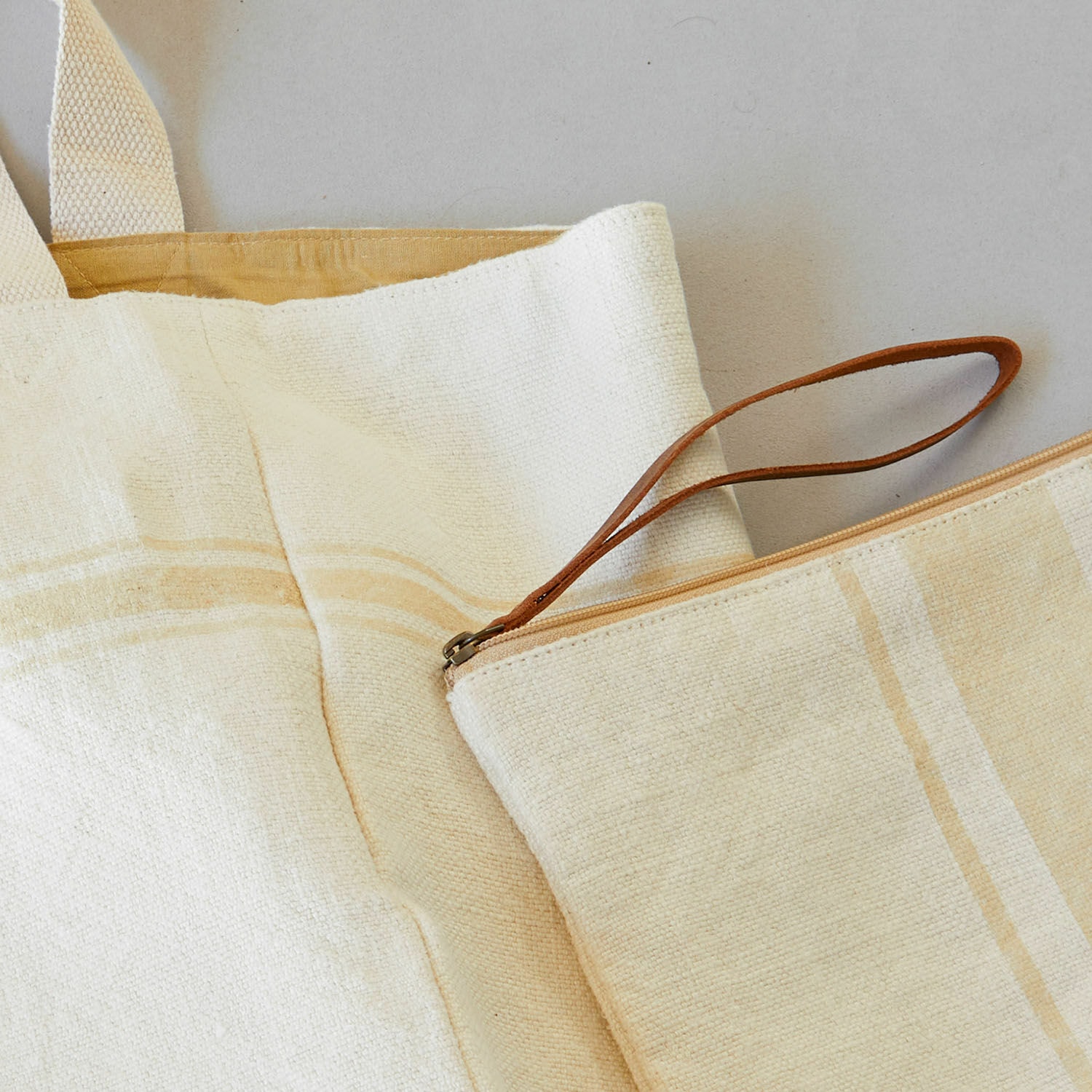 Beige Baumwolltasche und Kosmetiktasche mit hellbraunen Streifen und Ledergriff am Reißverschluss