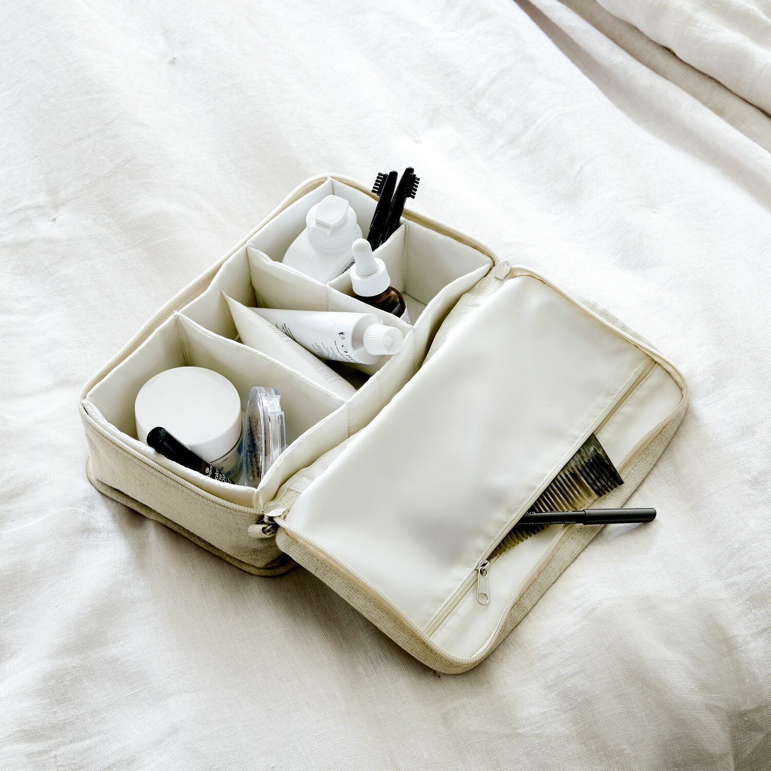 Beige Stoff-Kosmetiktasche mit Fächern und Reißverschluss, ideal zur Organisation von Pflegeprodukten