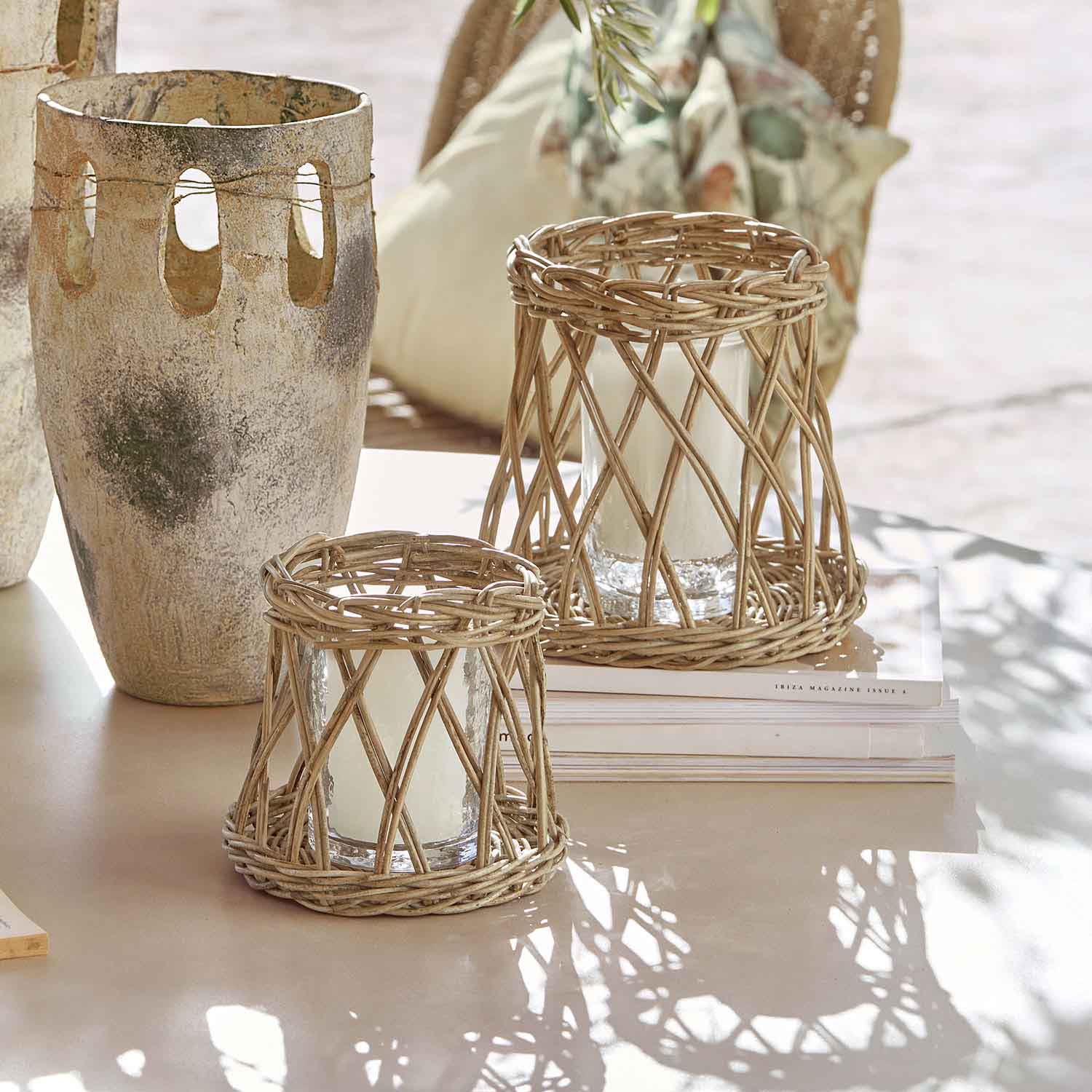 Zwei Windlichter aus natürlichem Rattan mit weißen Kerzen auf hellem Tisch, Wohnaccessoire