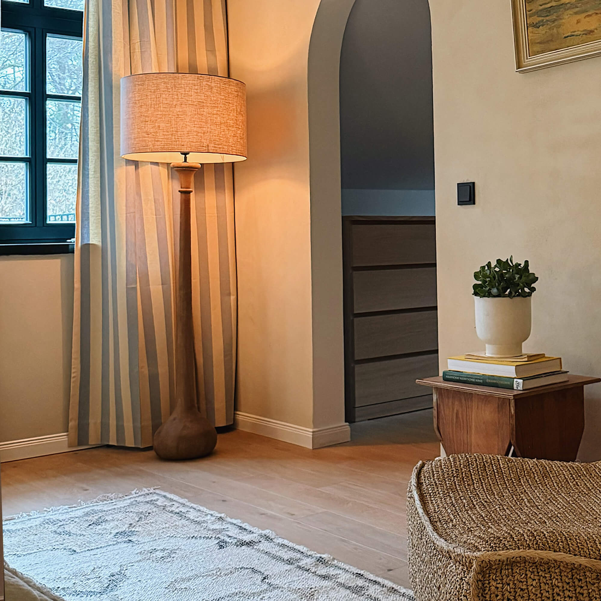 Stehlampe mit Holzfuß und beigem Lampenschirm in gemütlichem Wohnzimmer mit Teppich