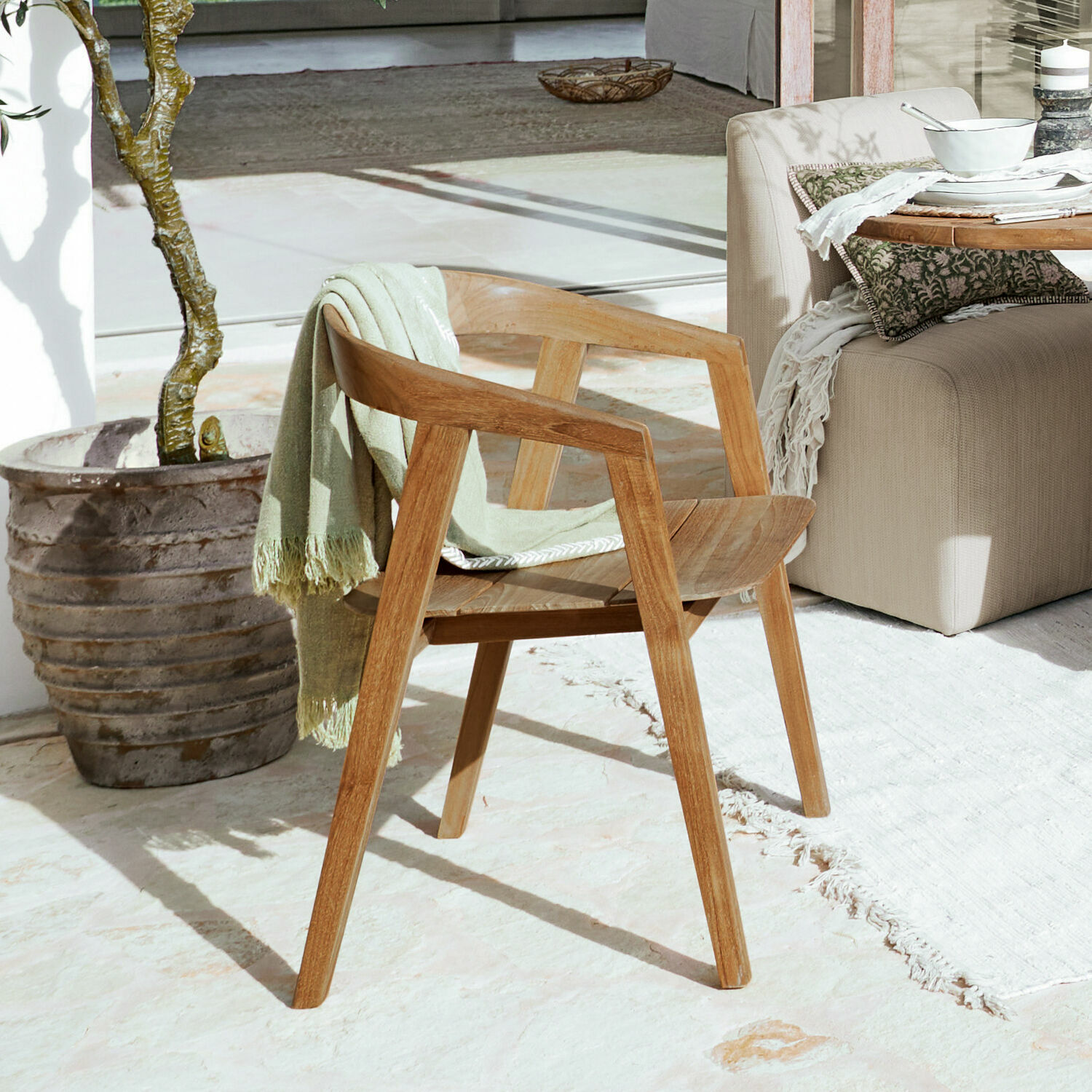 Stuhl Saulny Holzstuhl in Naturfarbe mit Armlehnen und grünem Plaid auf sonniger Terrasse