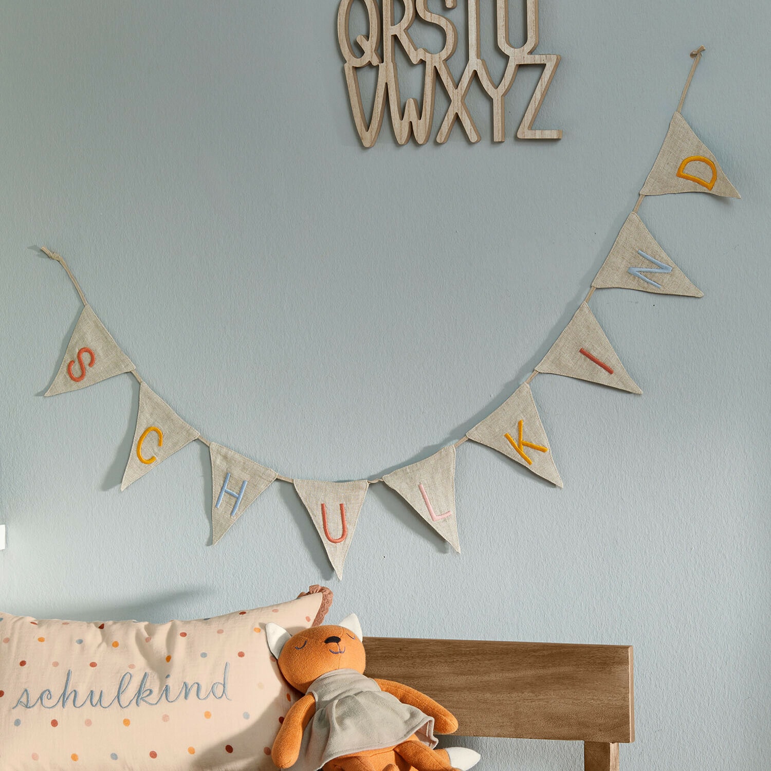 Wimpelgirlande Wibbelu Stoffgirlande mit bunten Buchstaben SCHULKIND an hellblauer Wand im Kinderzimmer