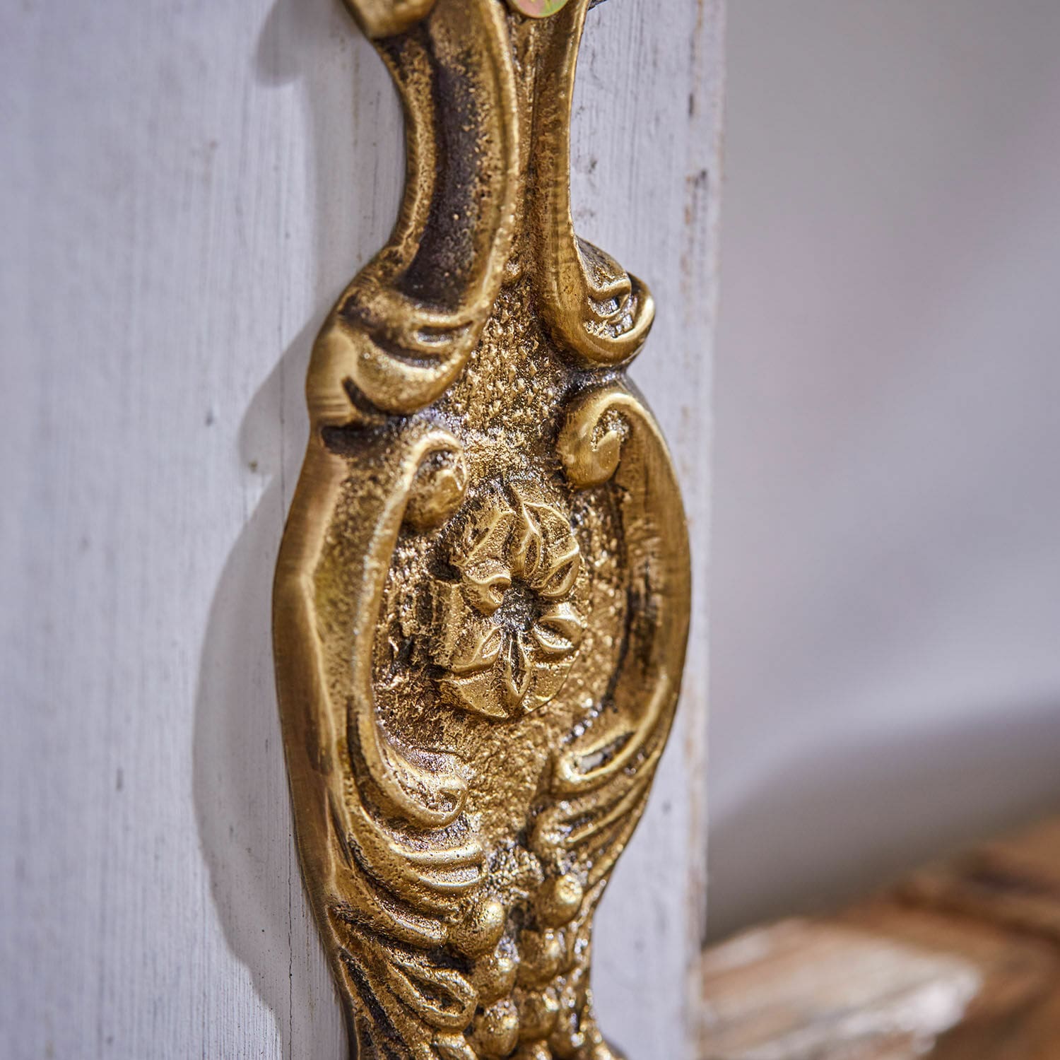 Goldfarbener Messing-Möbelknauf mit dekorativem Vintage-Design auf weißem Holz