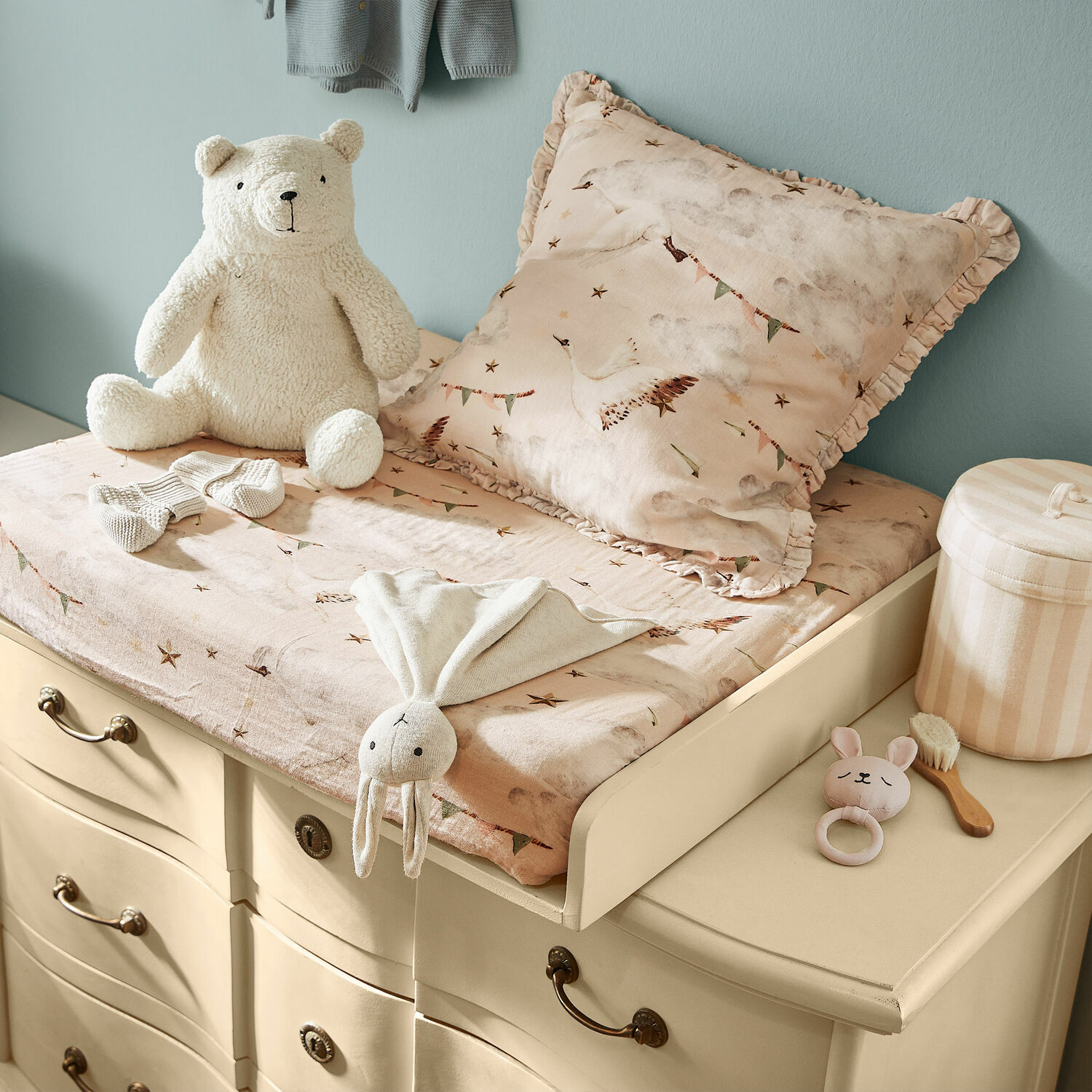 Beige Wickelkommode mit rosa Bettwäsche und Plüschtieren im Kinderzimmer