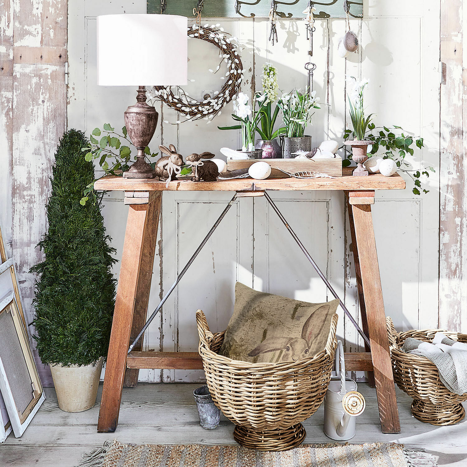 Holztisch mit Frühlingsdekoration, Weidenkörbe und rustikale Lampe im Landhausstil