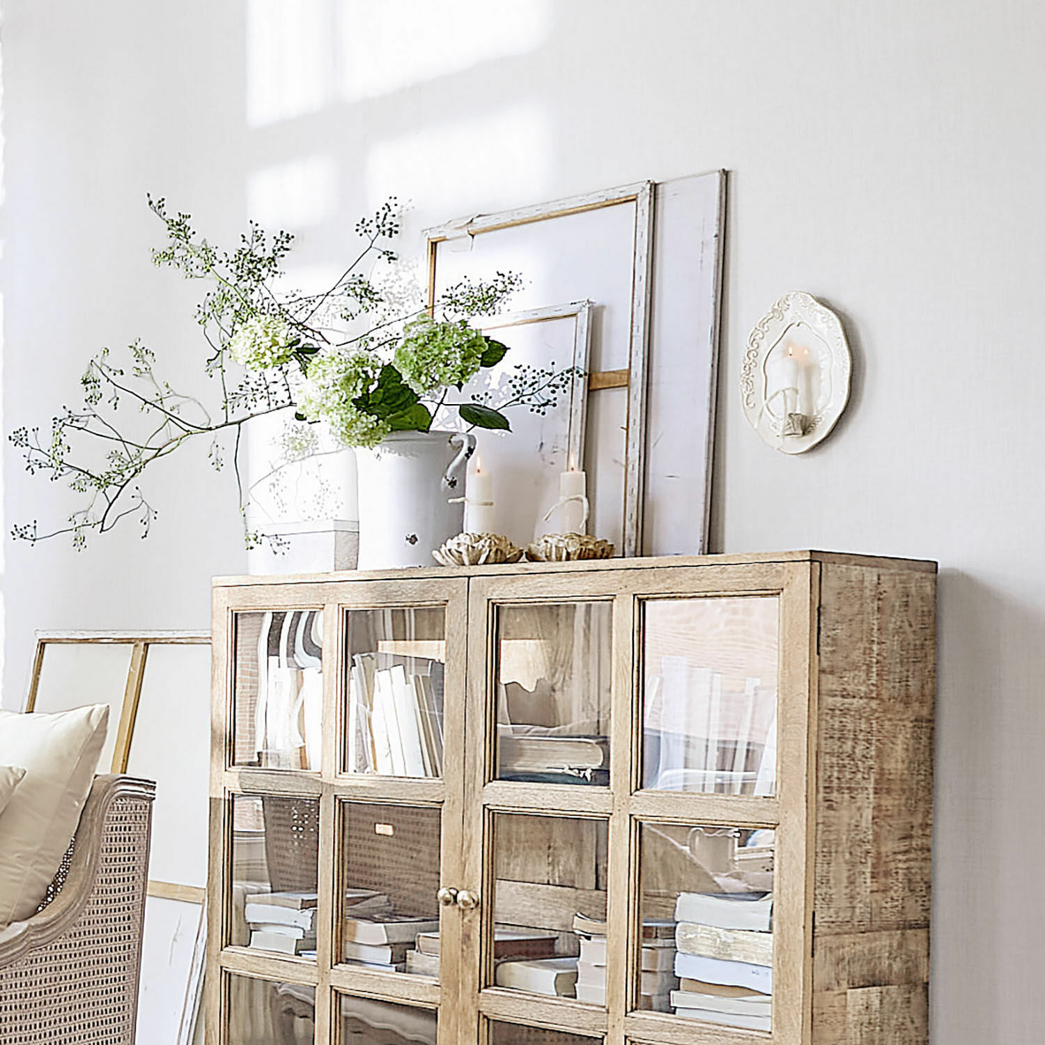 Helle Holzvitrine mit Glastüren, Dekorationen und Büchern in einem gemütlichen Wohnzimmer