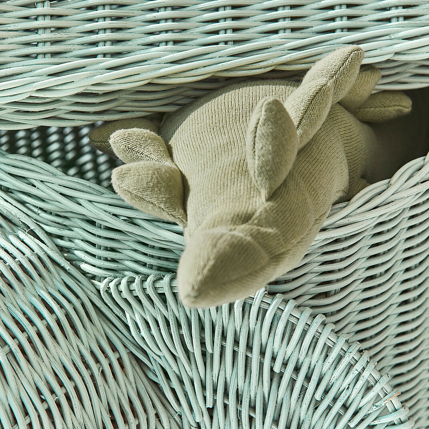 Beige Plüsch-Dinosaurier auf mintgrünem Korb aus geflochtenem Weidenholz zum Verstauen