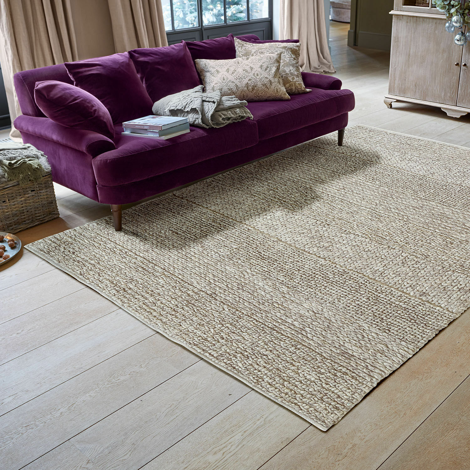 Teppich Welezas Heller Teppich aus Naturmaterial auf Holzboden unter violettem Samtsofa im Wohnzimmer