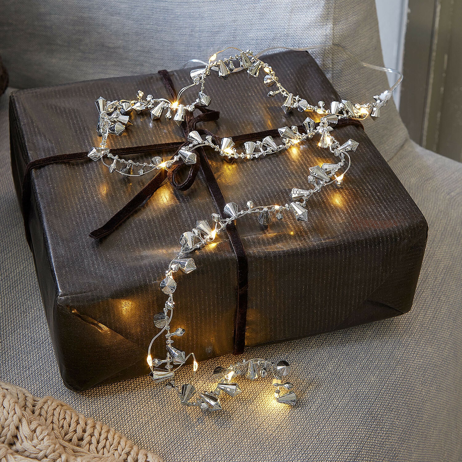 Lichterkette Bryesa Feine Lichterkette mit silbernen Metallanhängern auf dunklem Geschenkpaket dekorativ drapiert