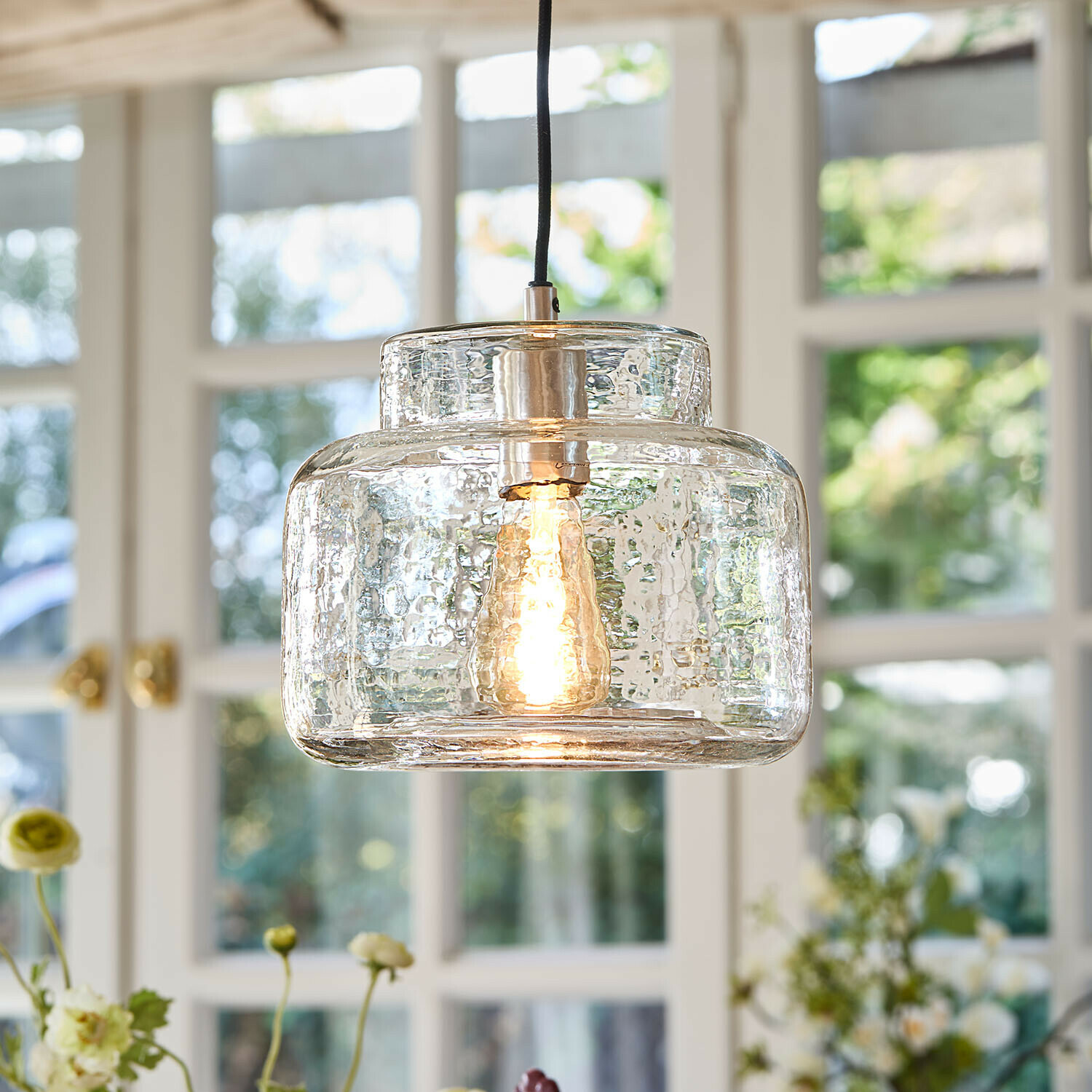 Hängelampe Vernadoux Hängelampe aus klarem, strukturiertem Glas mit warm leuchtender Glühbirne im Wohnraum