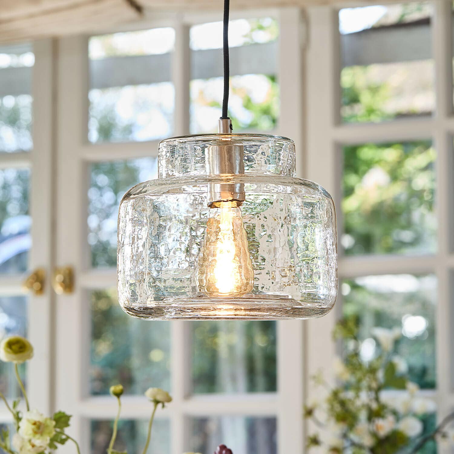 Hängelampe Vernadoux Hängelampe aus klarem, strukturiertem Glas mit warm leuchtender Glühbirne im Wohnraum