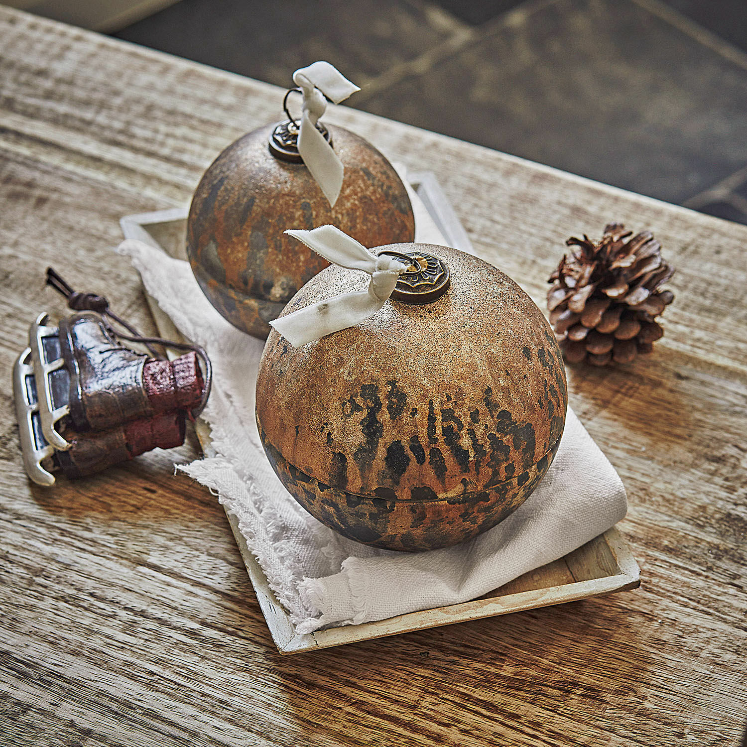 Dekorative braune Metallkugeln mit weißem Band auf Holztisch mit Weihnachtsdeko