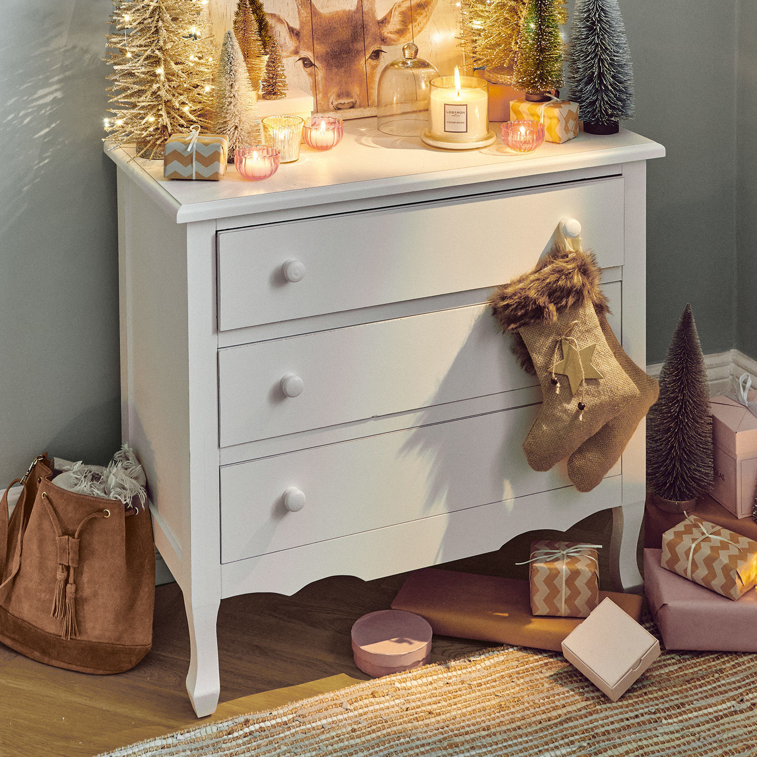 Weiße Holzkommode mit drei Schubladen, dekoriert mit Weihnachtsdeko und Geschenken