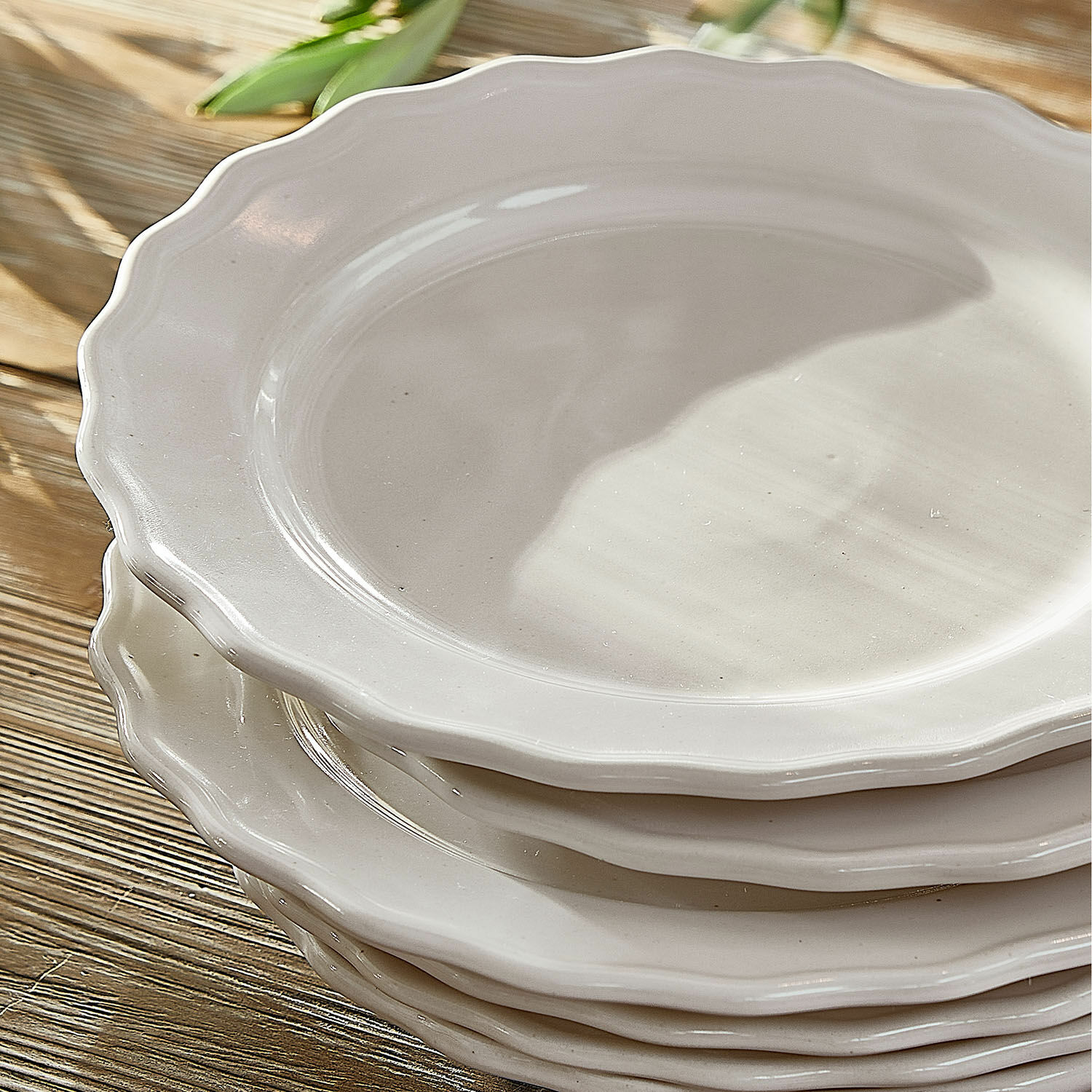 Set aus weißen Keramiktellern mit dekorativem Rand auf Holztisch, elegante Geschirrserie