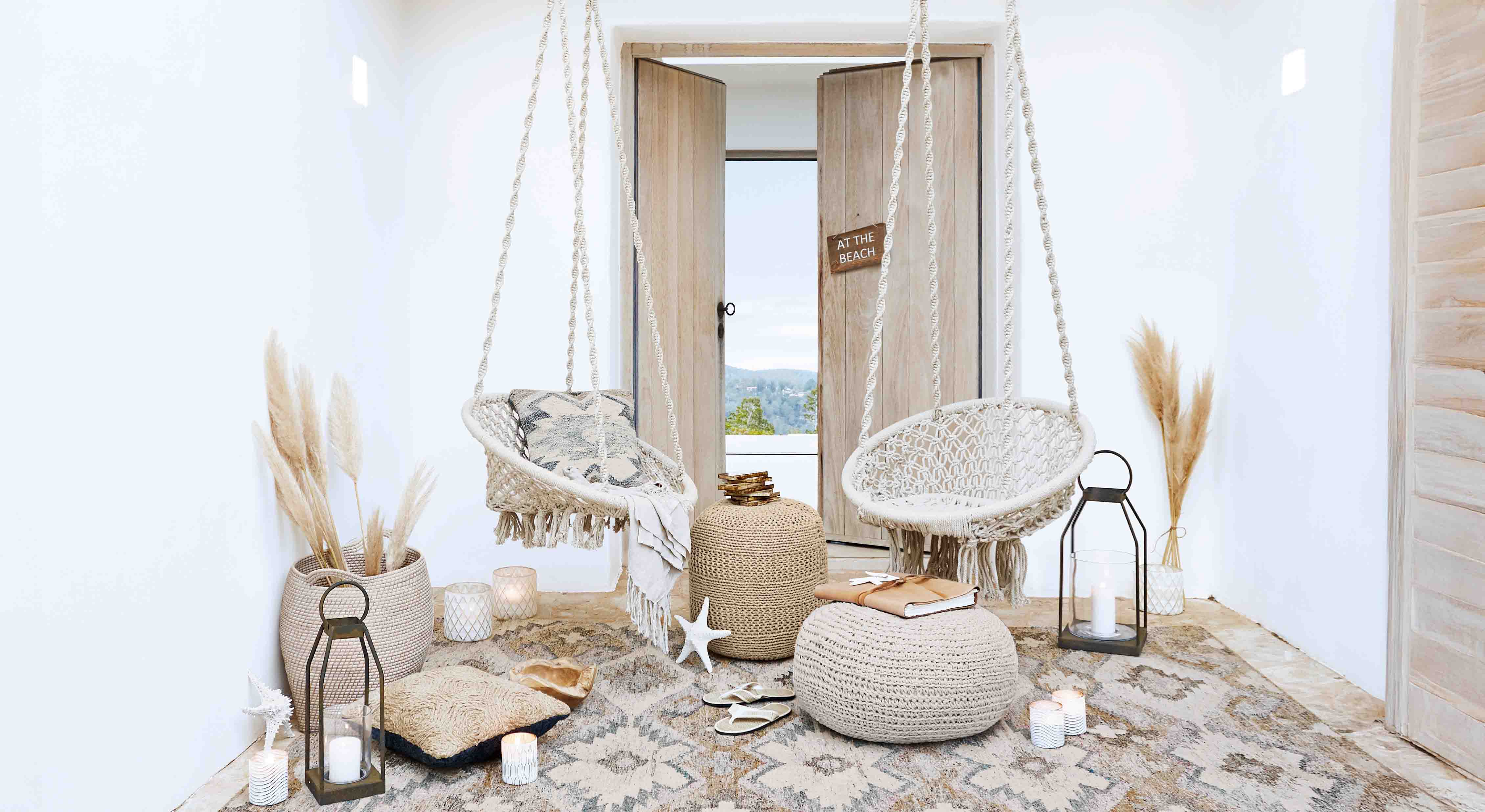 Gemütliches Wohnzimmer mit weißen Makramee-Hängesesseln und natürlichen Boho-Dekorationen
