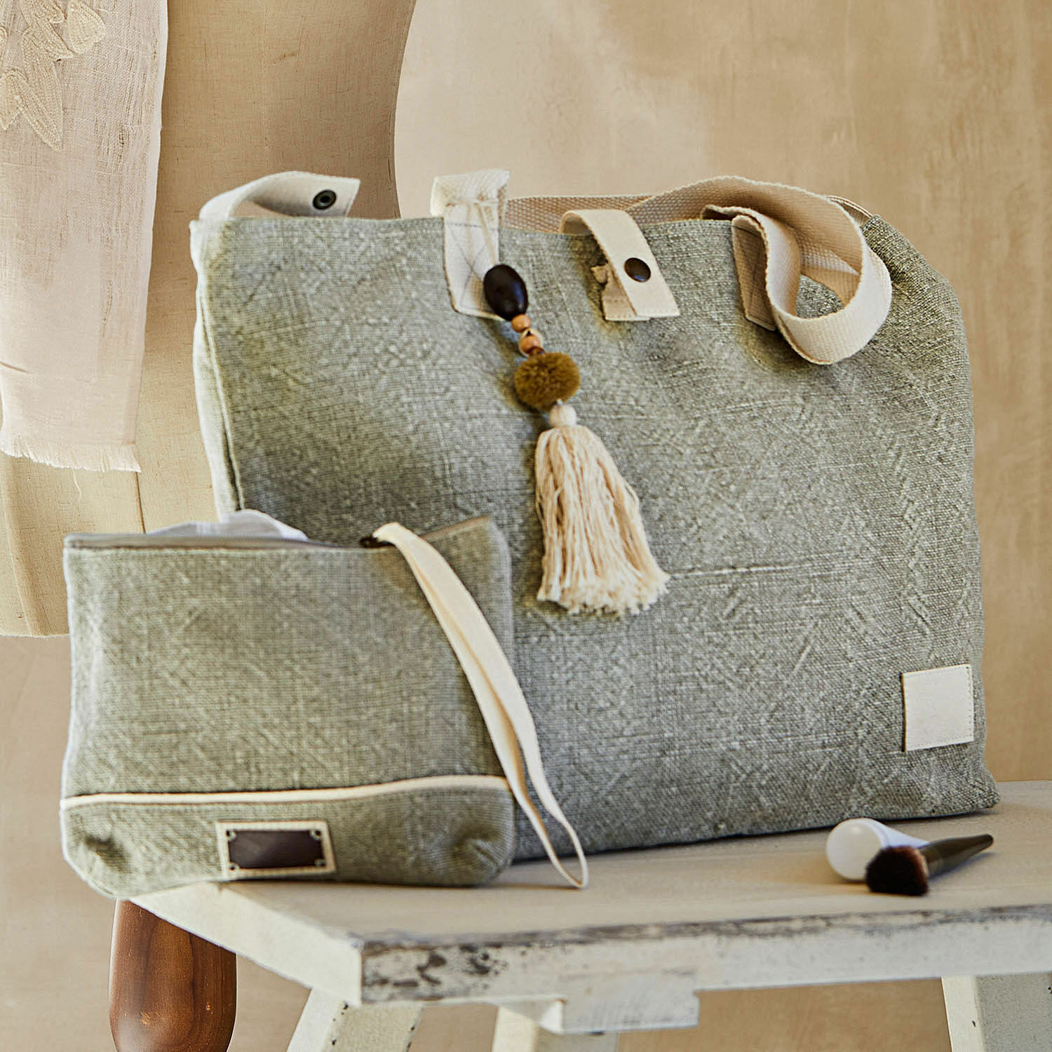 Set aus grauer Stofftasche mit cremefarbenen Griffen und dekorativem Quastenanhänger, Tasche und Kosmetiktasche