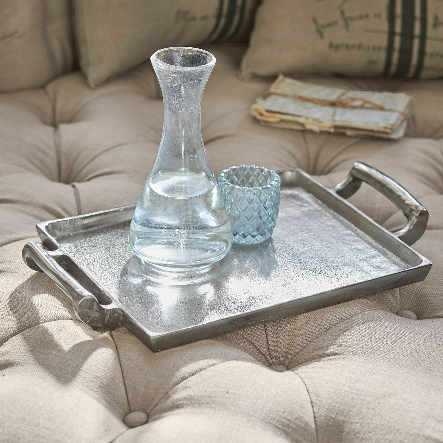 Tablett Connaire Dekoratives silbernes Metalltablett auf beigem, gesteppter Polsterung mit Glas-Karaffe und Becher