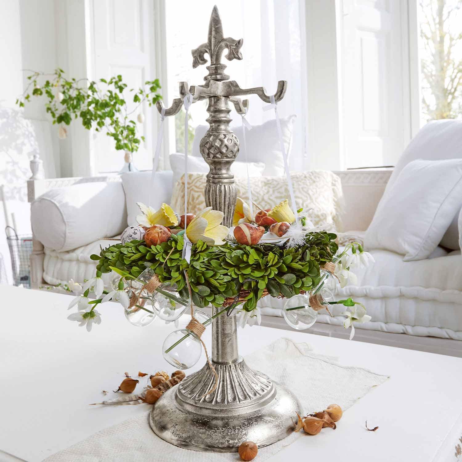 Metallische Tischdekoration mit grünem Kranz und Glaskugeln auf weißem Tisch in hellem Wohnzimmer