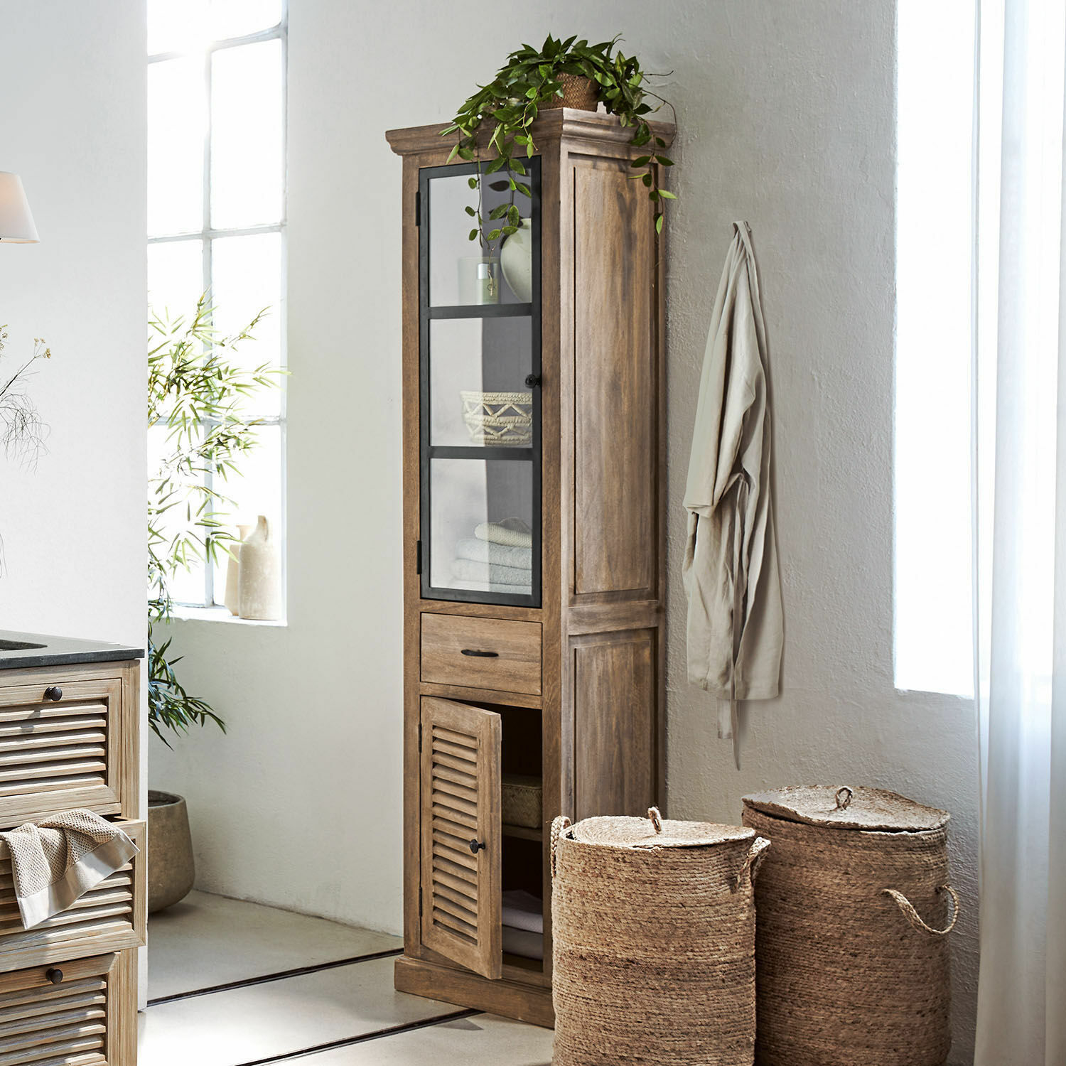 Hoher Schrank aus Mangoholz in Natur mit Glastür und Schublade zur Aufbewahrung im Raum