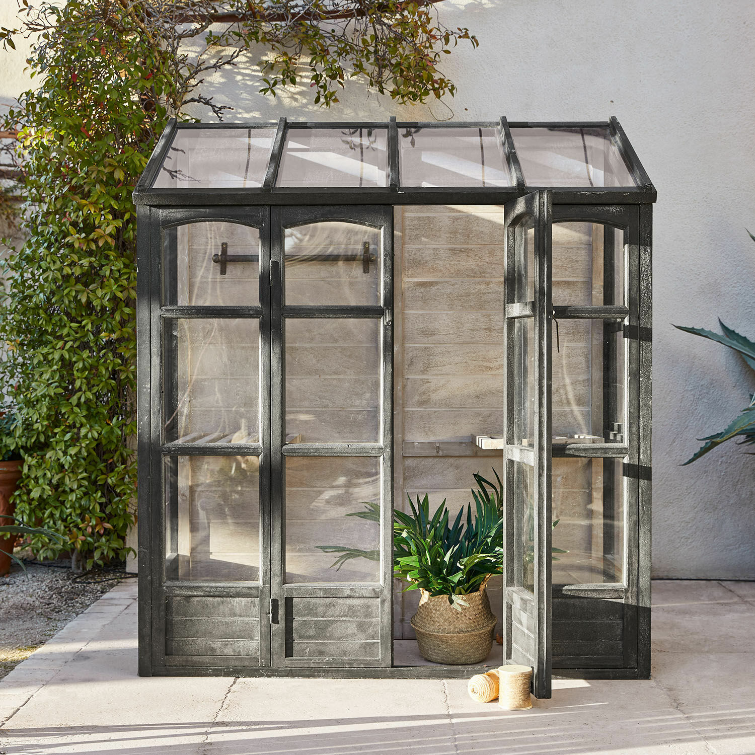 Gartengewächshaus mit schwarzem Metallrahmen, ideal für Pflanzenzucht und Gartenarbeit.