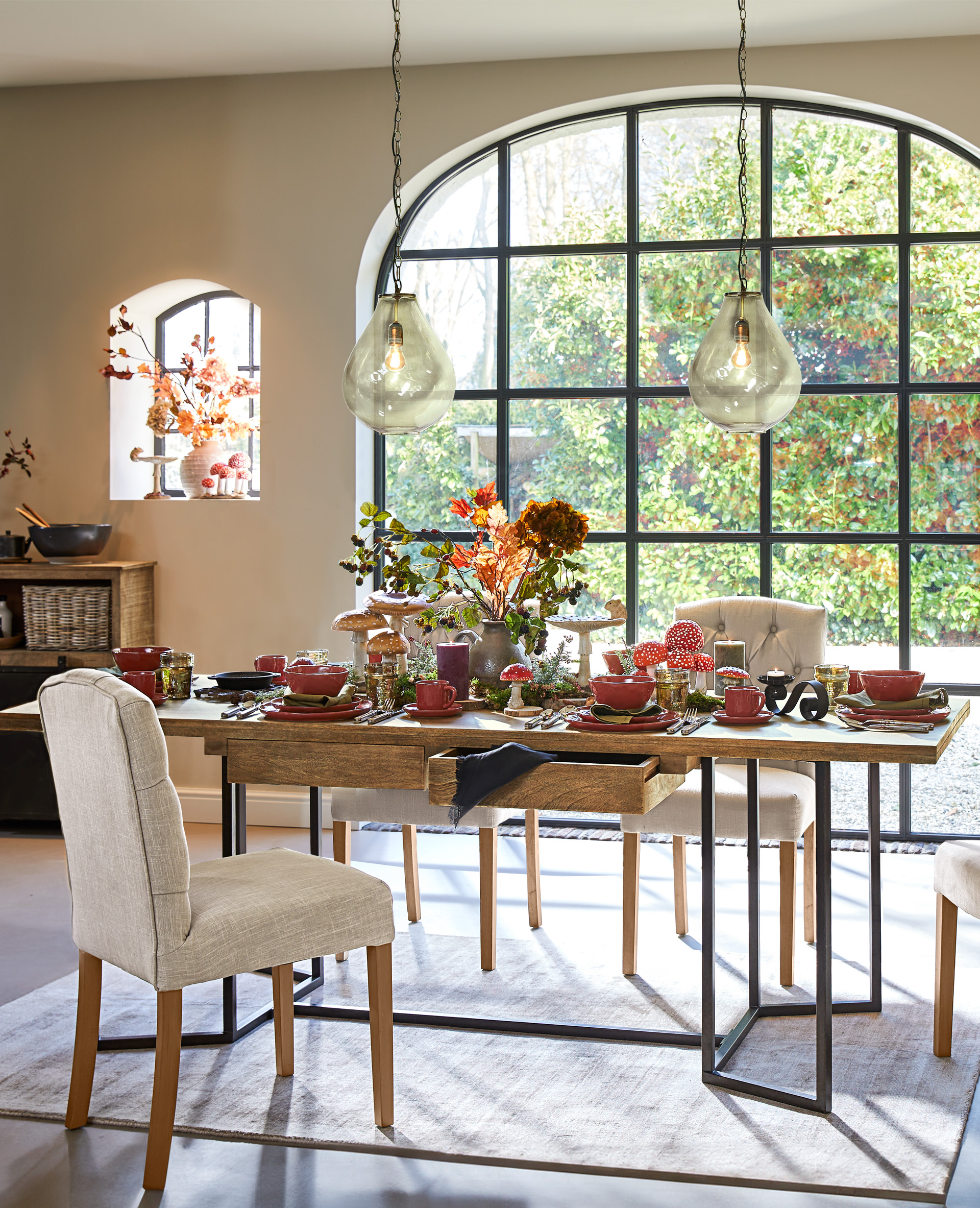 Esszimmer mit Holztisch und beige gepolsterten Stühlen vor großem Fenster mit Tischdekoration