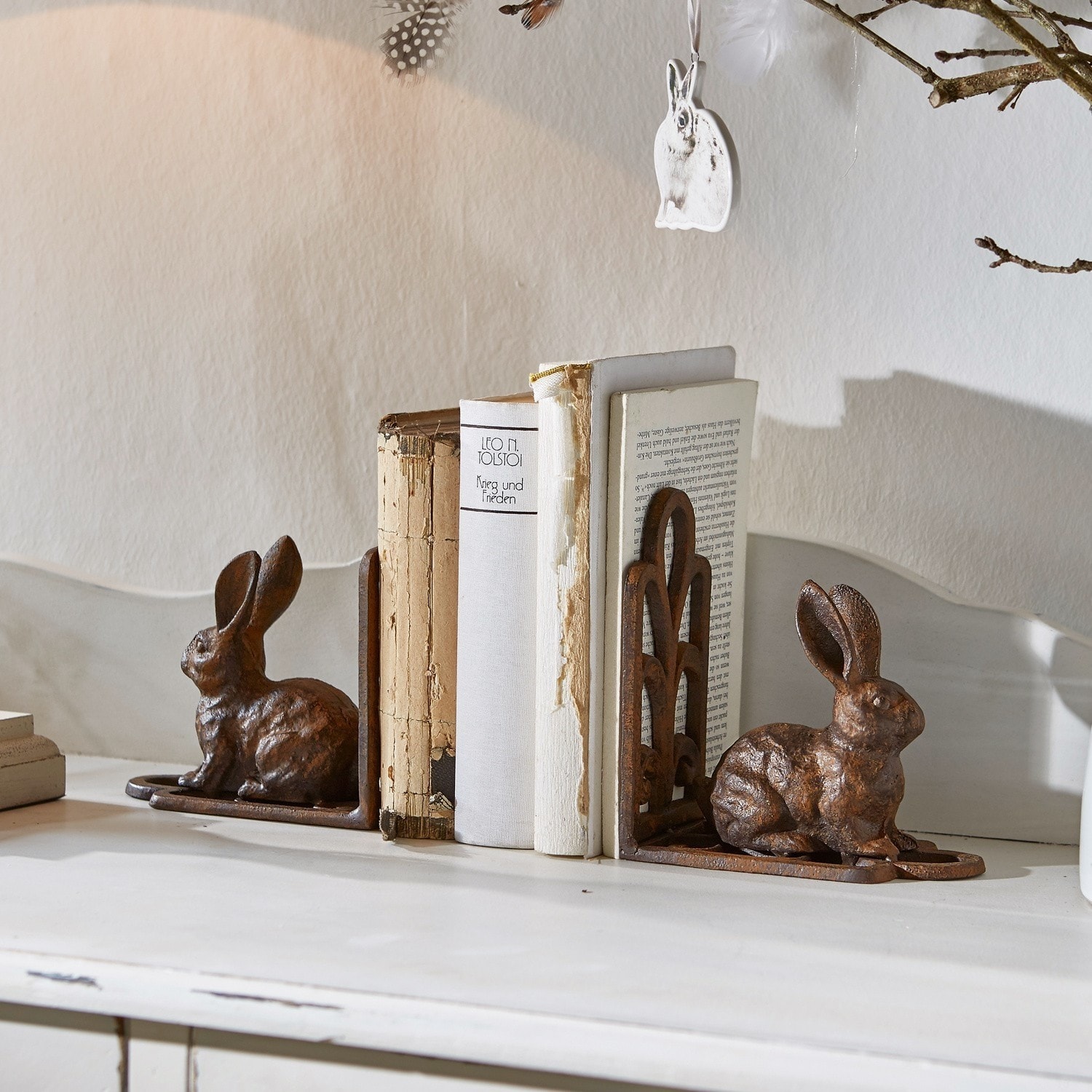 Set aus rostfarbenen Metall-Buchstützen mit Hasenmotiv auf weißem Tisch für Wohnkultur