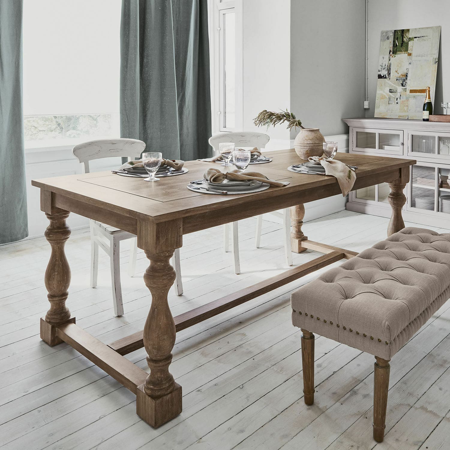 Holz-Esstisch mit gedrechselten Beinen und beige gepolsterter Bank in hellem Raum