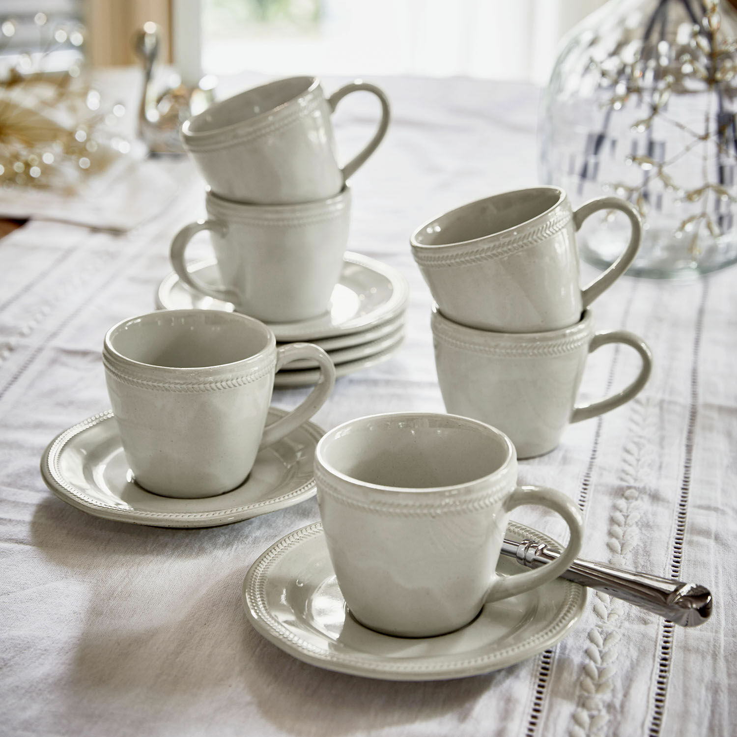 Tasse mit Untertasse 6er Set Norrvik Set aus weißen Keramiktassen mit Untertassen auf weißem Tischtuch für Kaffee und Tee