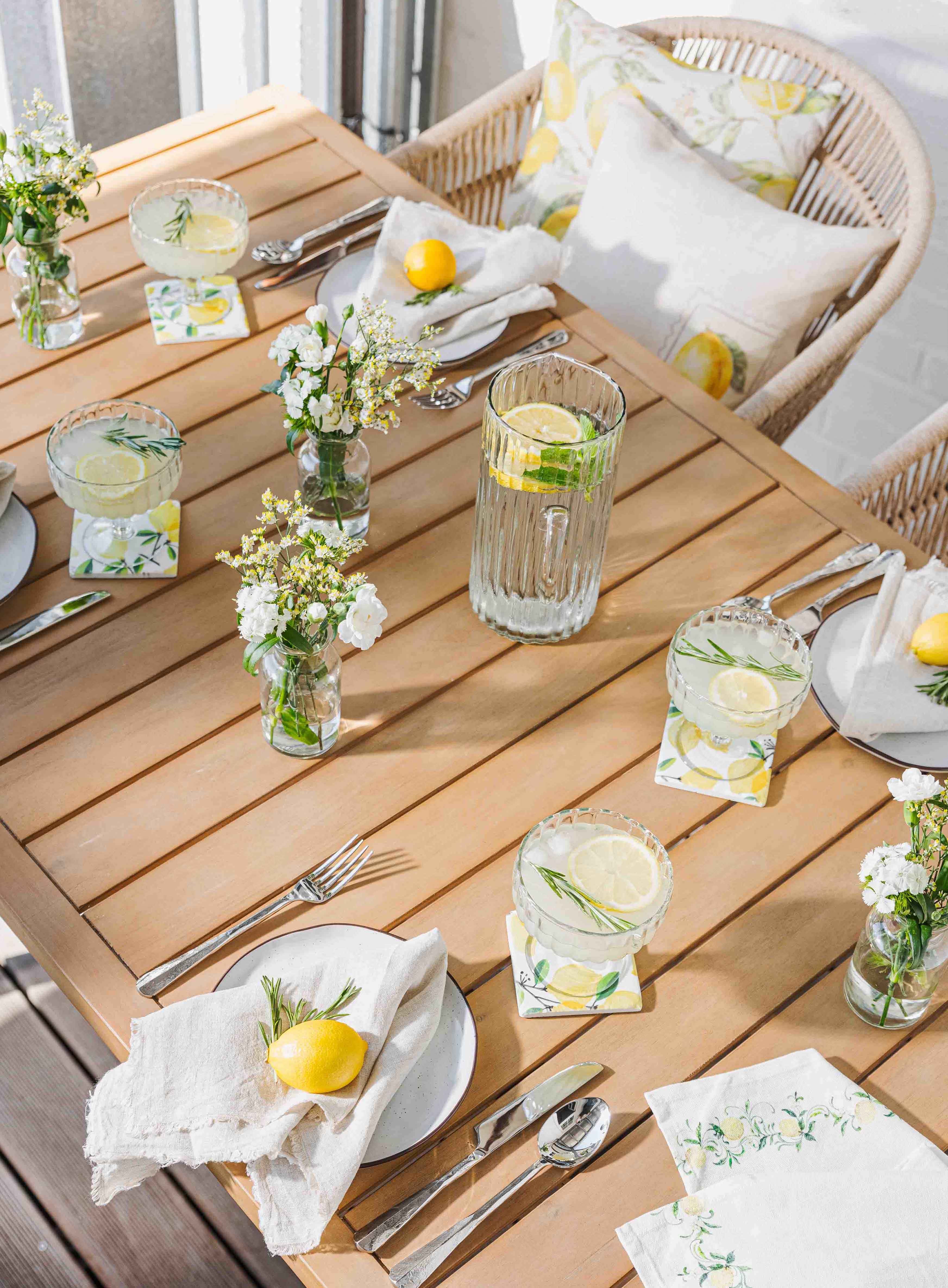 Heller Holztisch mit Limonade, Gläsern und Zitronendekor für sommerliches Gartentisch-Setting