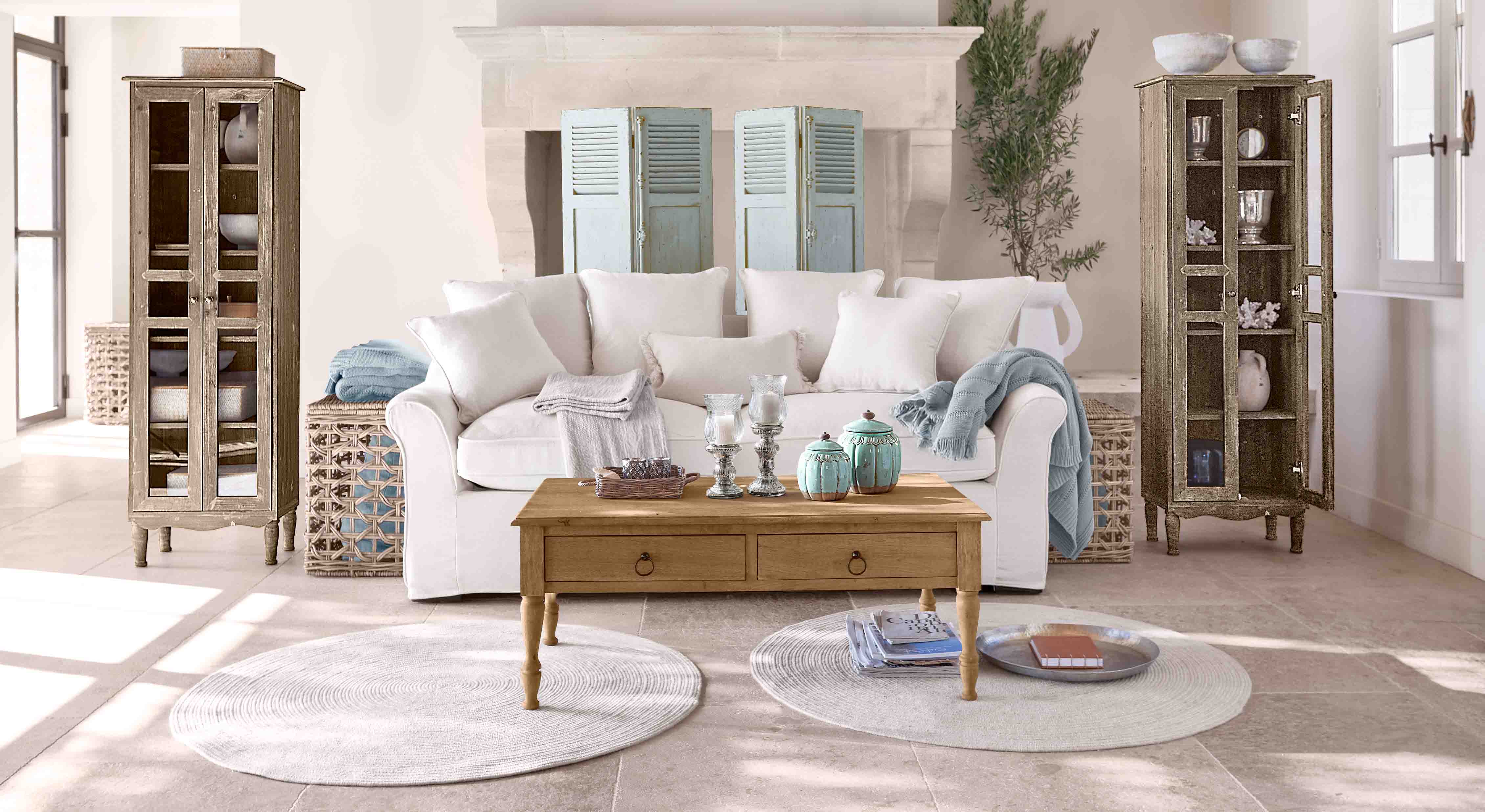 Gemütliches Wohnzimmer mit weißem Sofa, Holztisch und zwei antiken Holzvitrinen