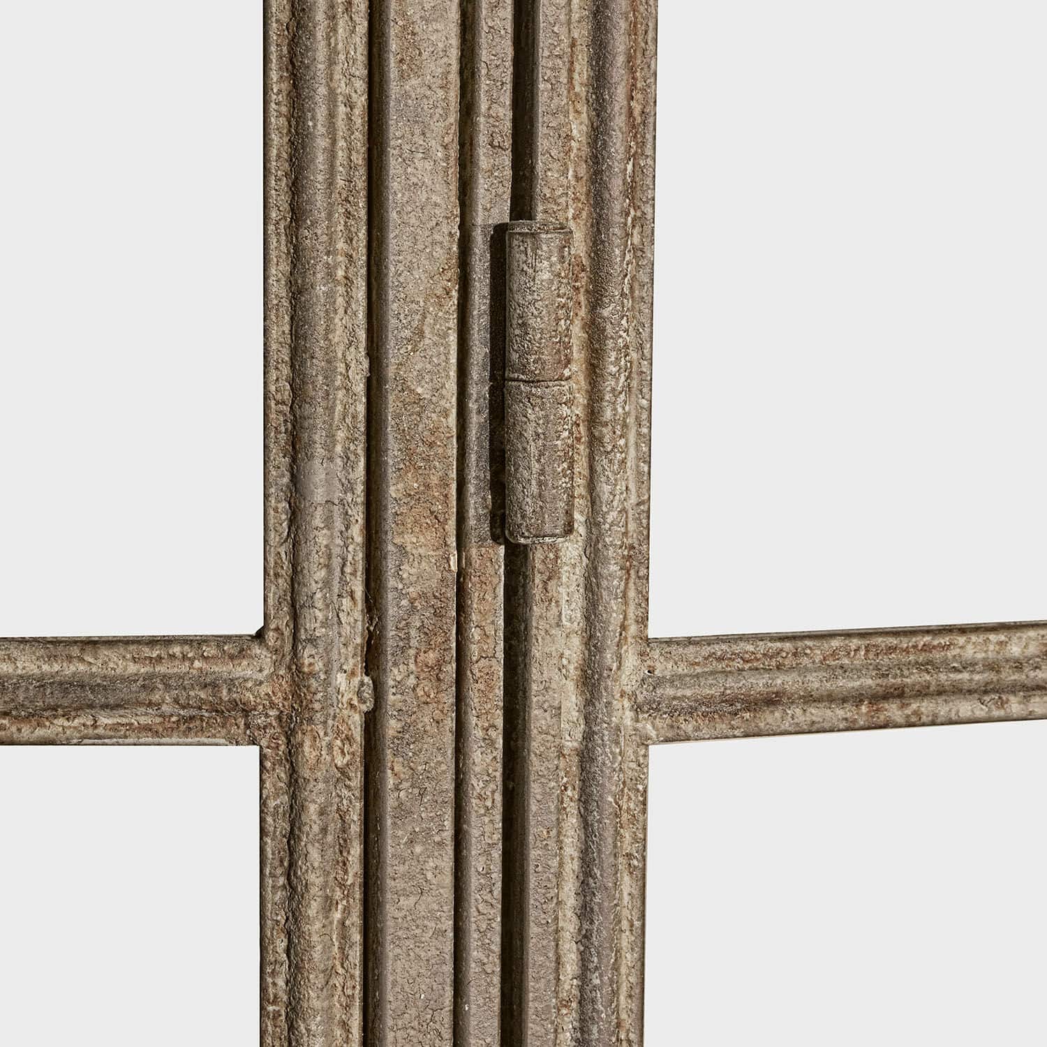 Nahaufnahme eines grauen, gealterten Metallfensterrahmens mit sichtbarem Scharnier