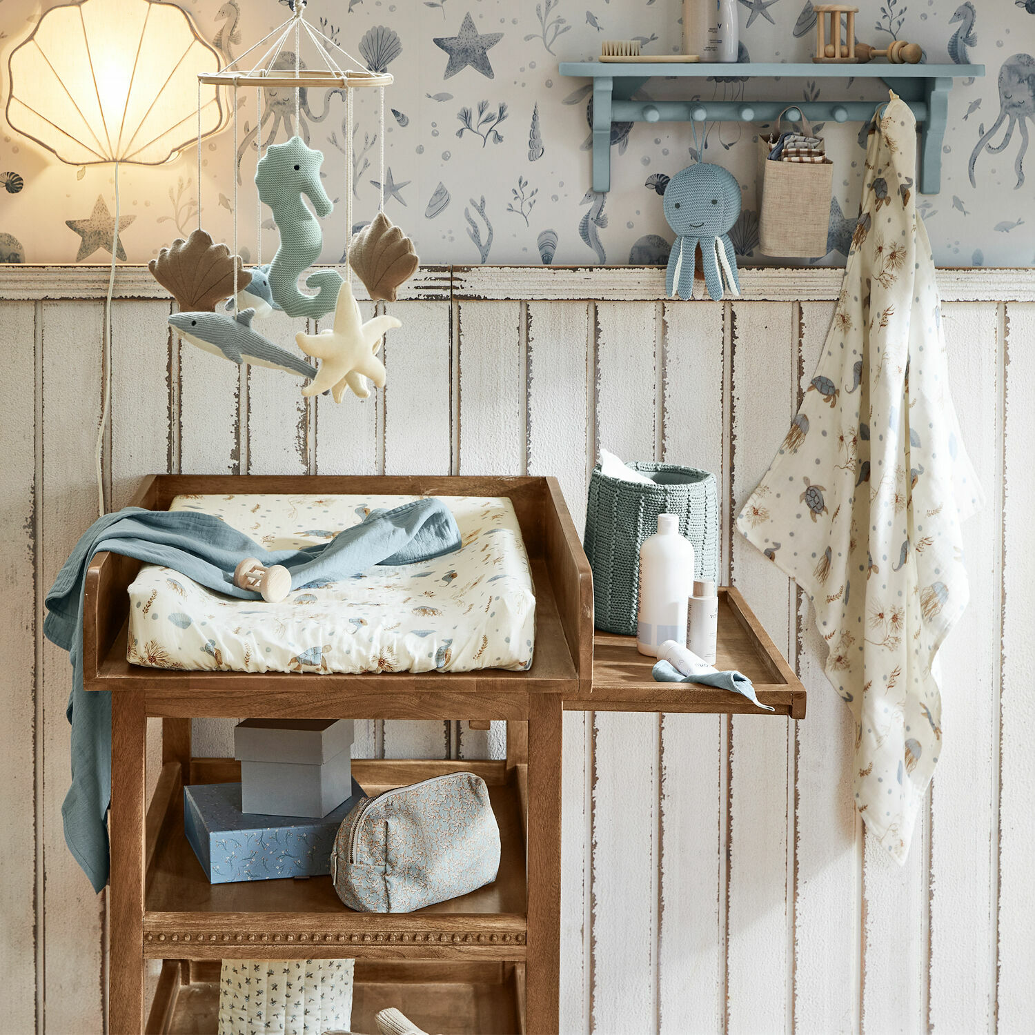 Holz-Wickeltisch mit maritimen Spielzeugen und pastellfarbenen Textilien im Kinderzimmer