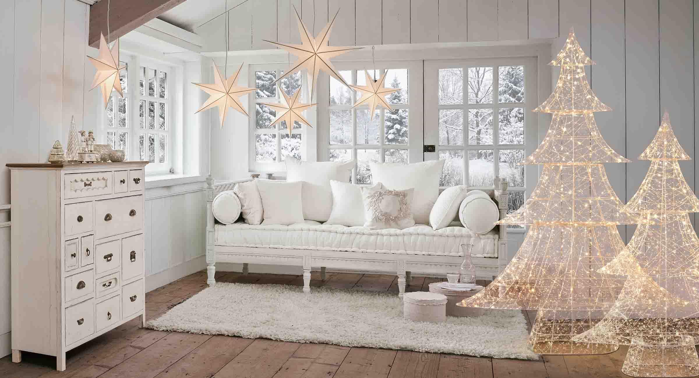 Gemütliches weißes Wohnzimmer mit leuchtenden Stern- und Tannenbaum-Dekorationen für den Winter