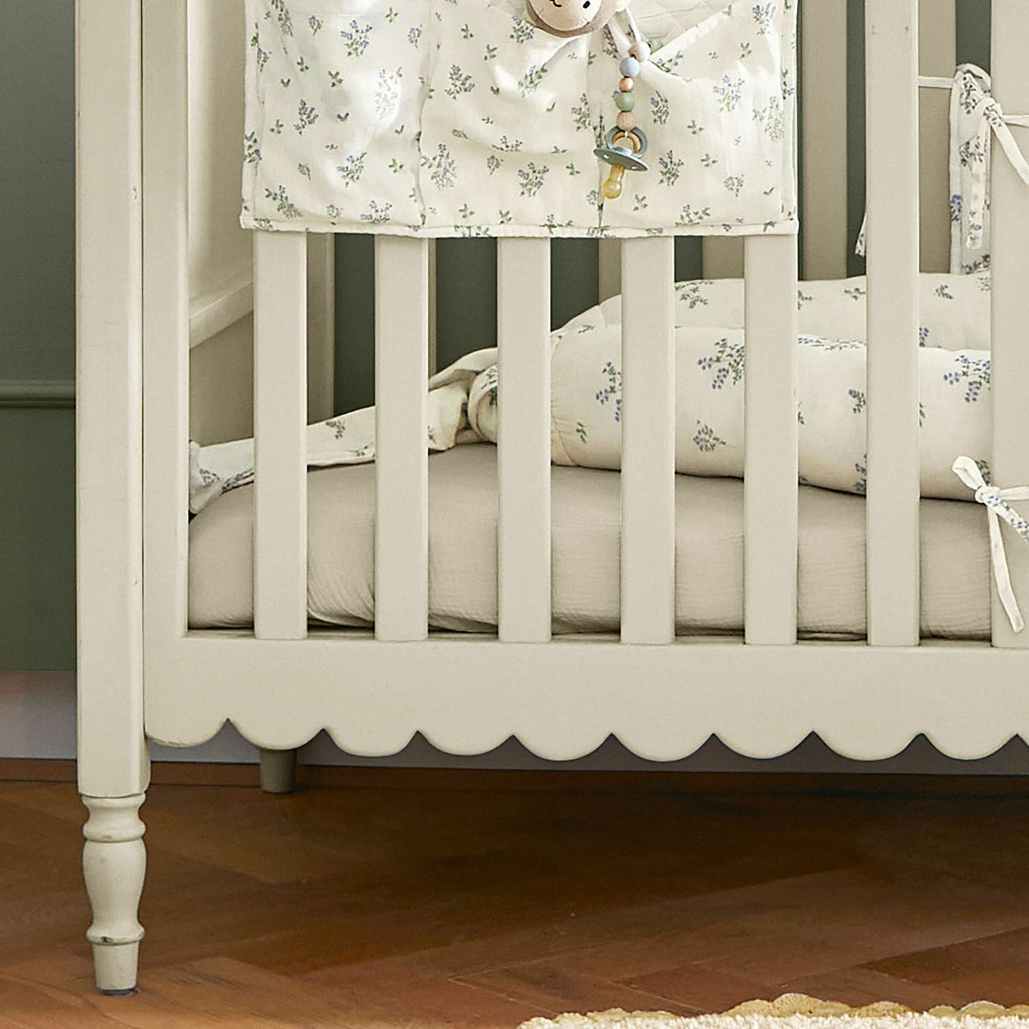 Beige lackiertes Kinderbett aus Holz mit floral gemusterter Bettwäsche und weicher Matratze