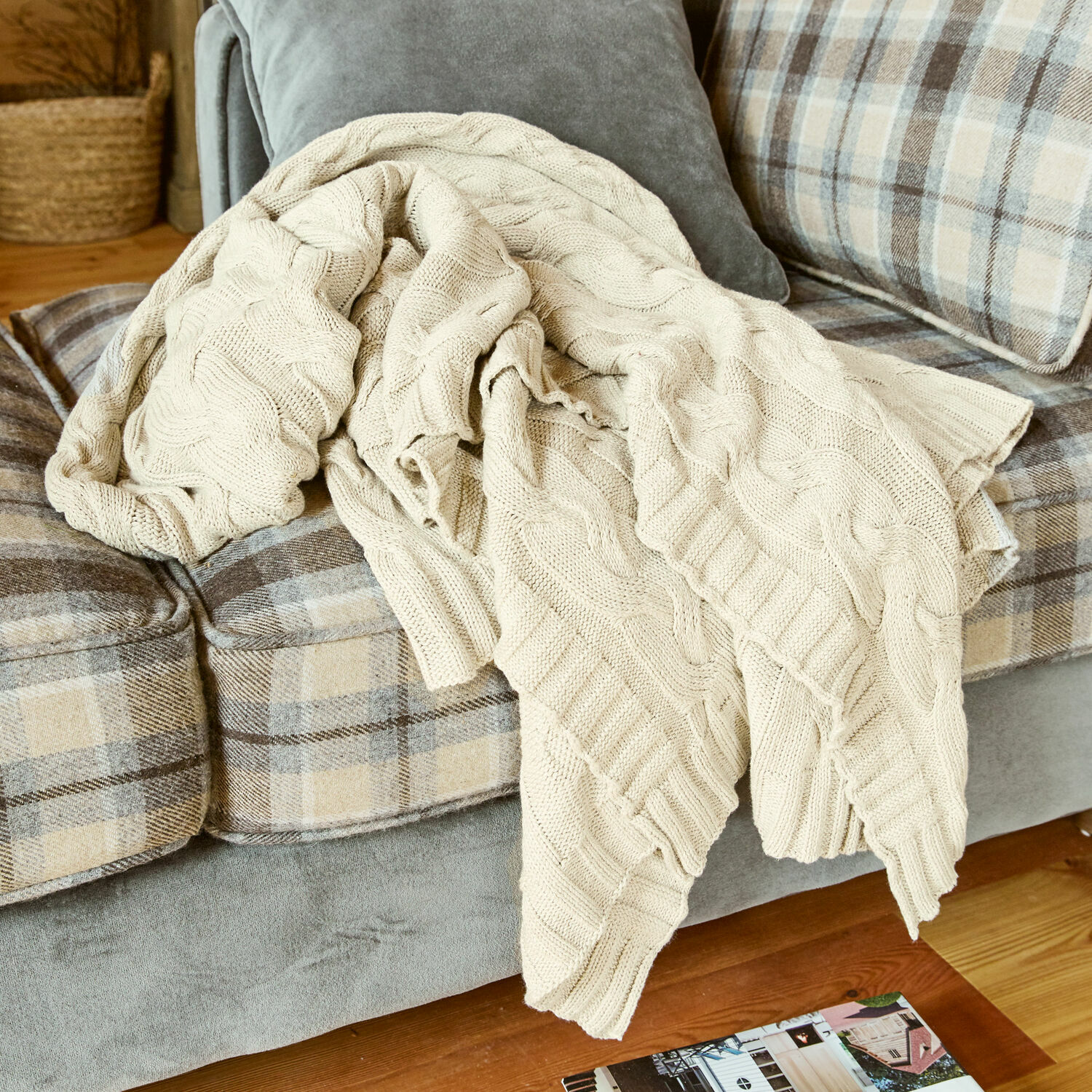 Plaid Arnhem Beige gestrickte Baumwolldecke auf grauem Sofa mit beigem Karomuster im Wohnzimmer