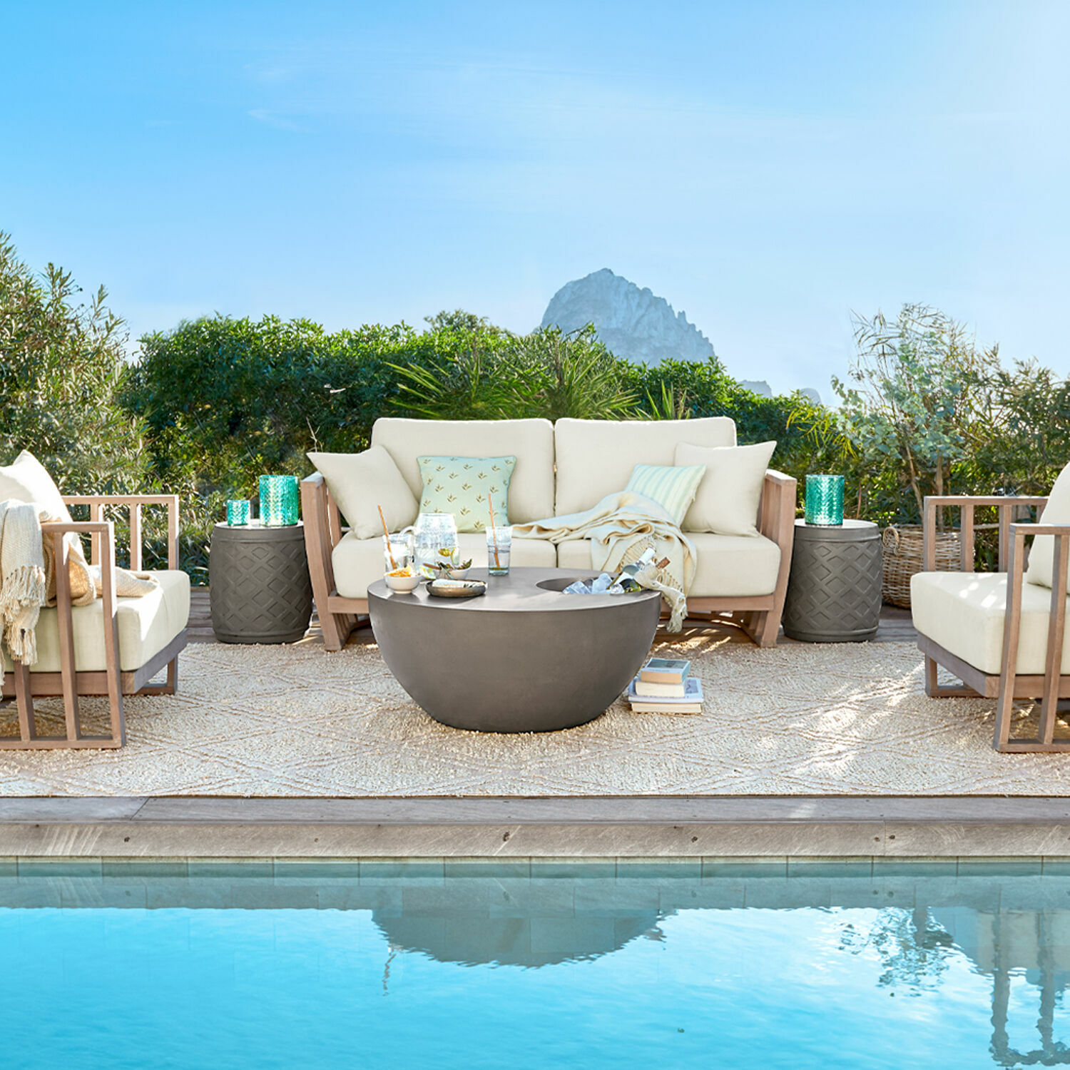 Gartenmöbel-Set mit beigen Polstern und grauem Betontisch am Poolrand